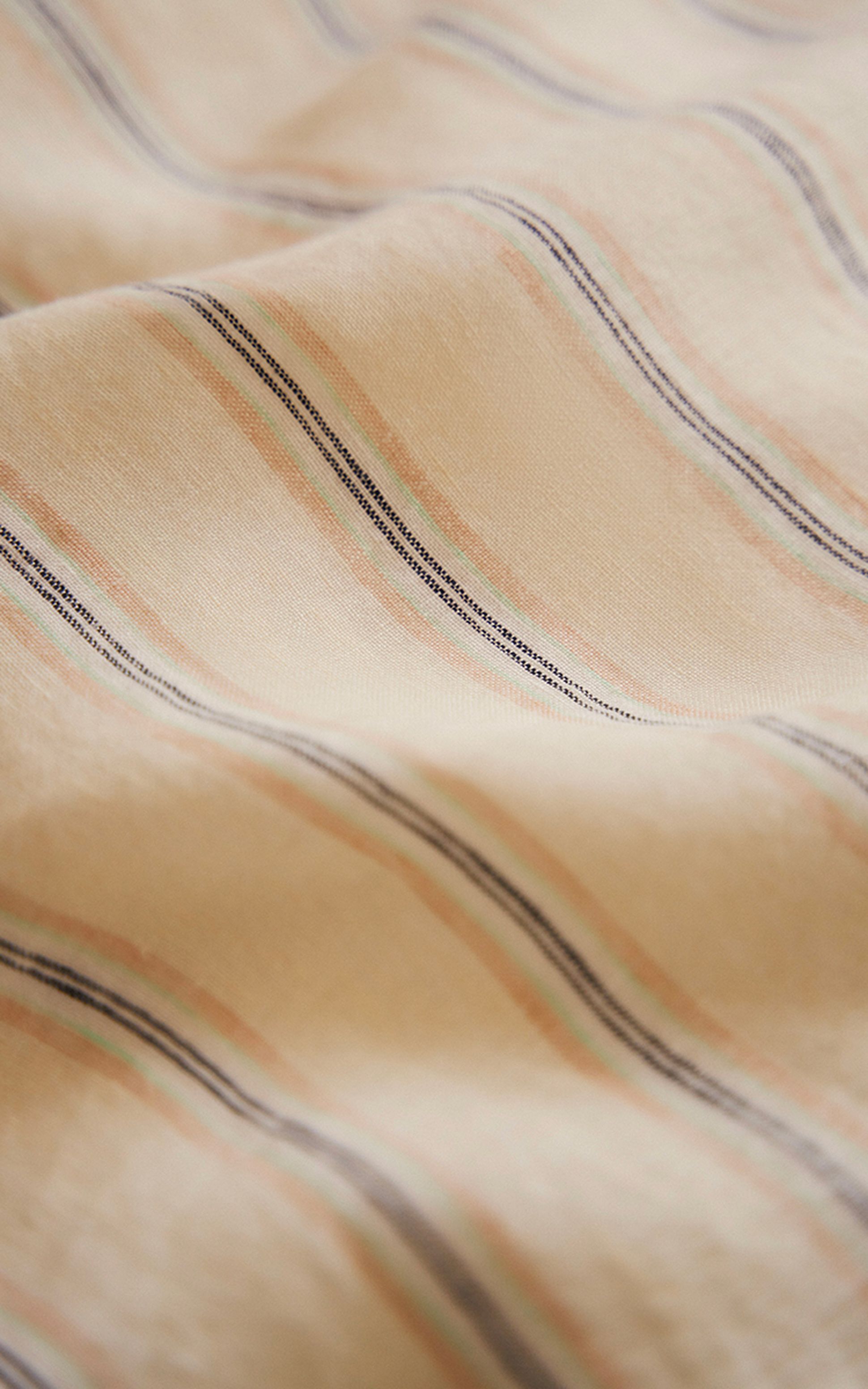 Gros plan sur un tissu beige orné de rayures diagonales aux tons pastel de rose, vert et bleu, qui lui confèrent un aspect doux et texturé.