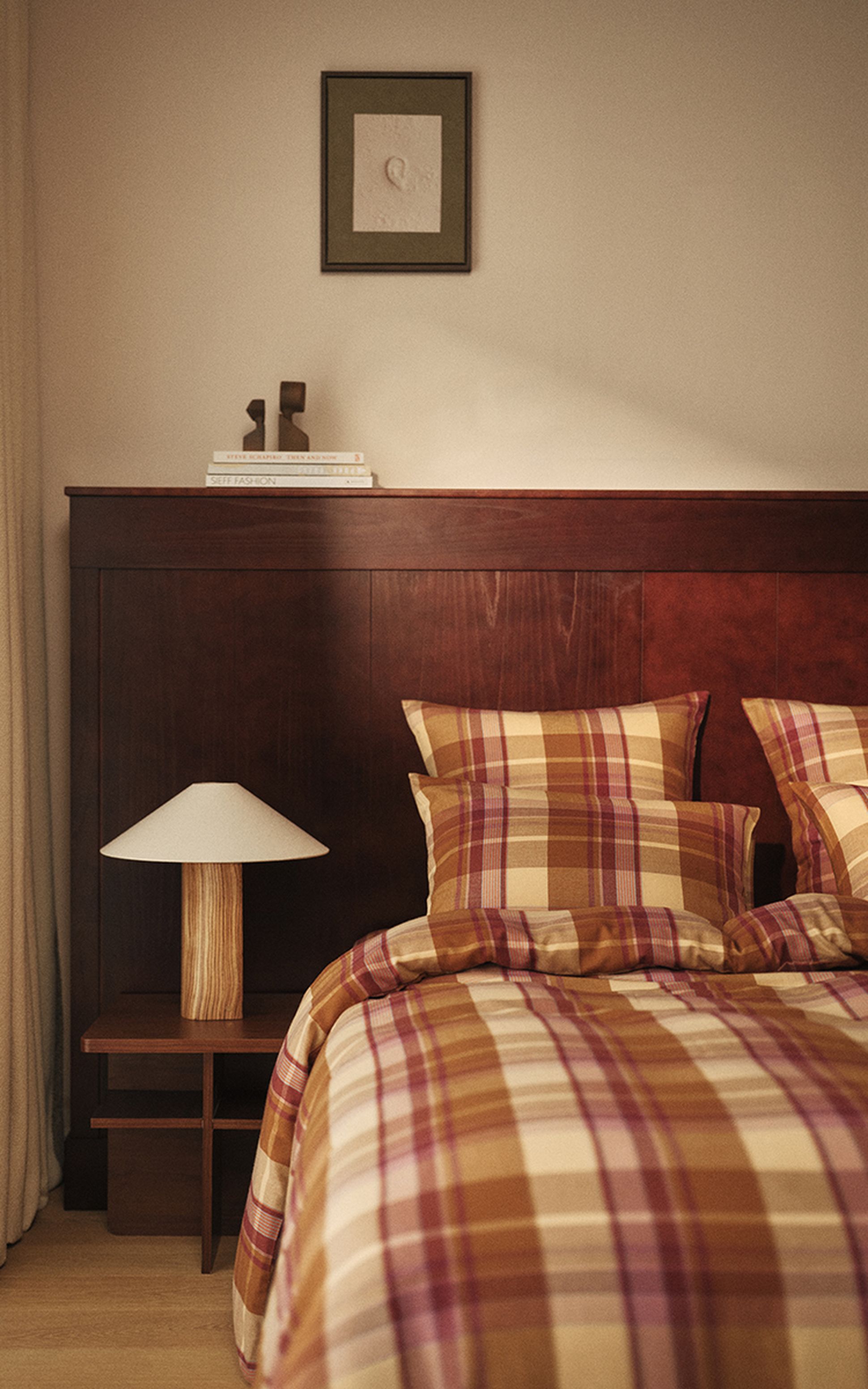 Ensemble de literie à carreaux dans les tons rouge, beige et jaune, agrémenté de deux oreillers assortis posés sur le lit, créant une ambiance chaleureuse et douillette.