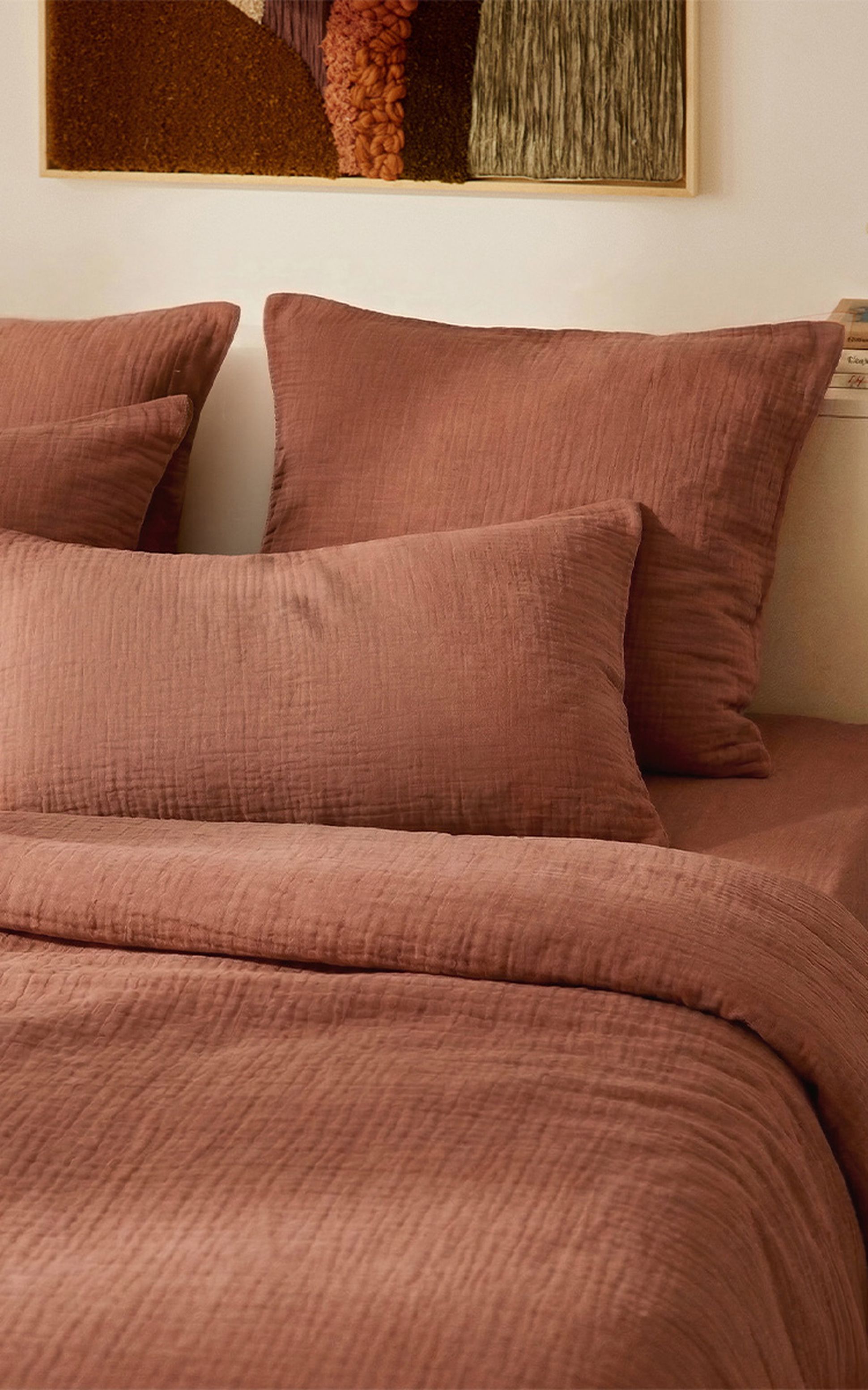Une chambre douillette avec un lit recouvert de draps doux couleur rose, dans un décor rustique baigné d'une lumière naturelle et chaleureuse.