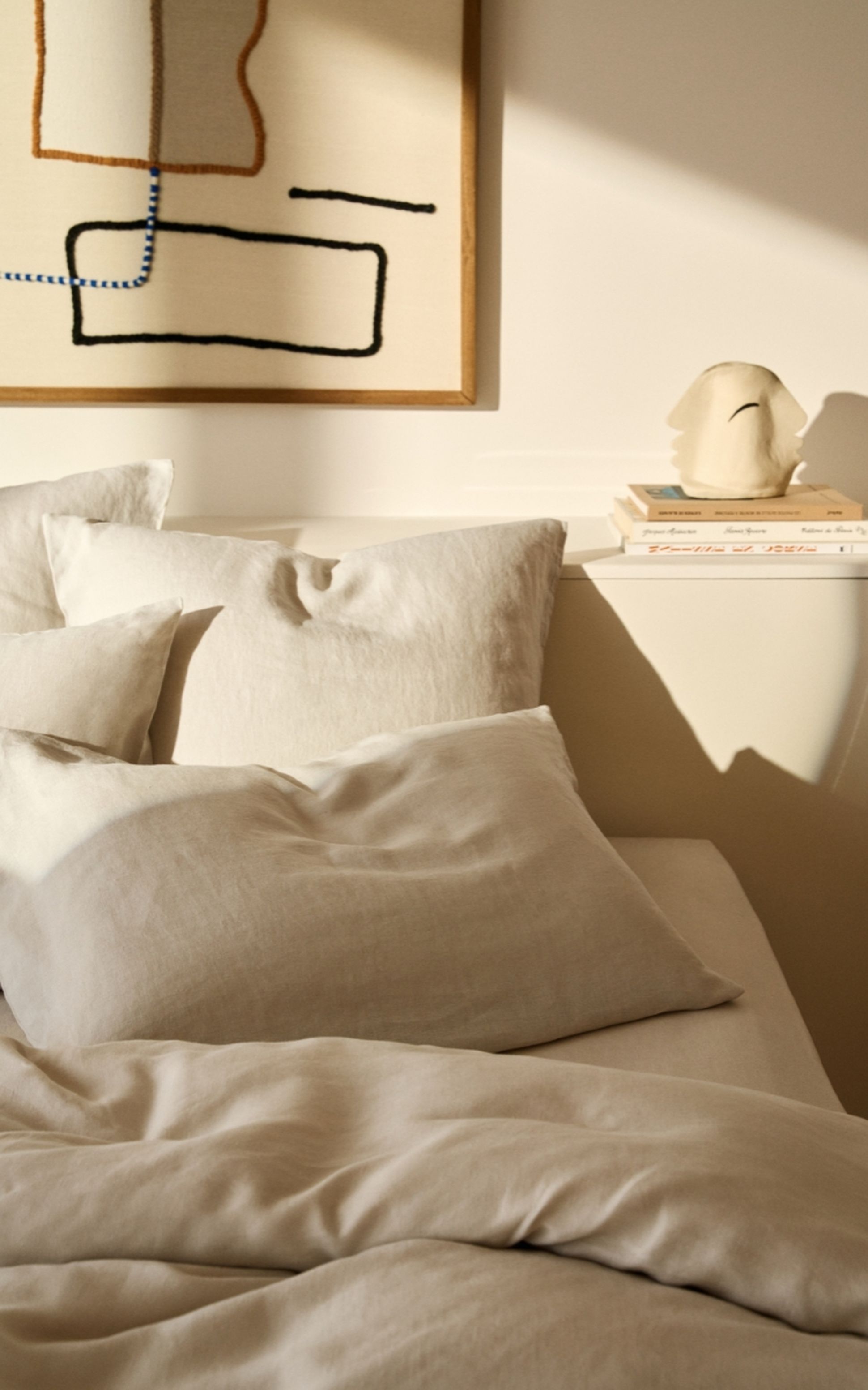 Chambre cosy avec une parure de lit en lin beige, baignée de lumière