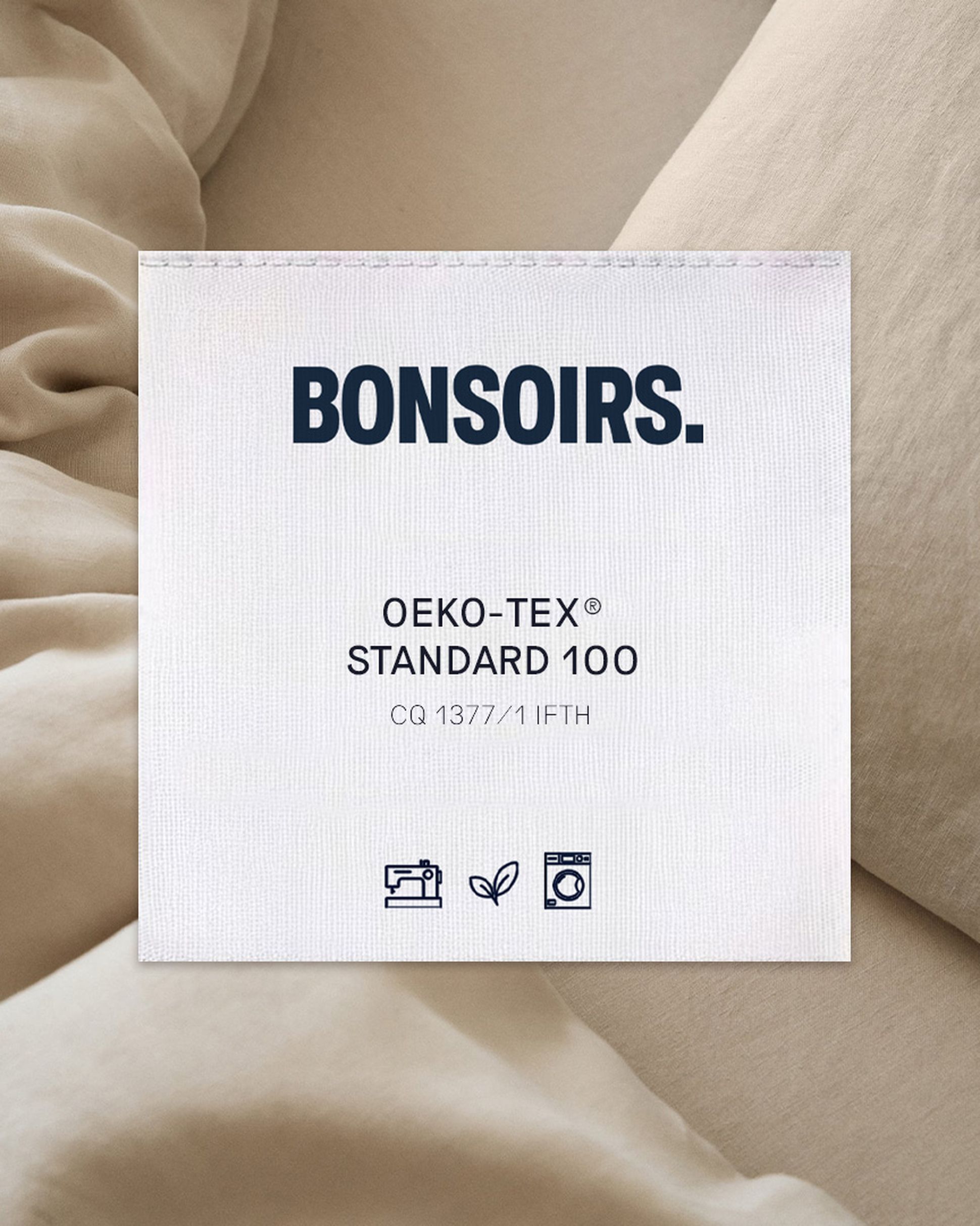 Étiquette portant la mention « BONSOIRS » sur un tissu, indiquant la certification « OEKO-TEX STANDARD 100 » avec des icônes relatives au lavage et au respect de l'environnement.