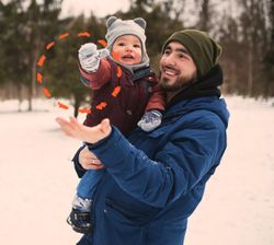 papà tiene in braccio un bambino in un paesaggio innevato