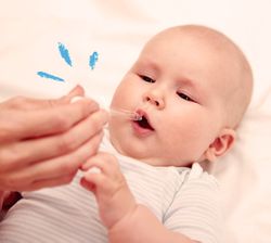 neonato che viene imboccato dalla mano della mamma con un contagocce