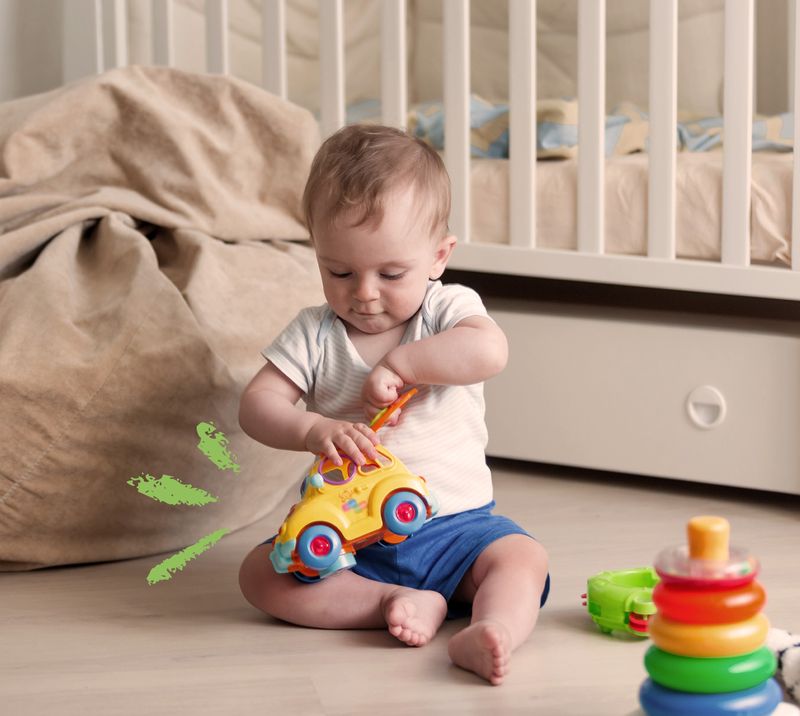 bambino seduto sul pavimento gioca con una macchinina