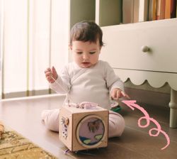 bambino seduto sul pavimento gioca con un cubo giocattolo
