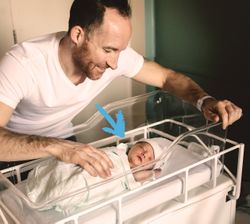 papà accarezza un neonato in una culla da ospedale