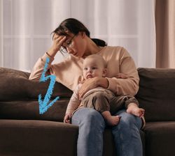 mamma seduta sul divano con bambino in braccio ed espressione affaticata