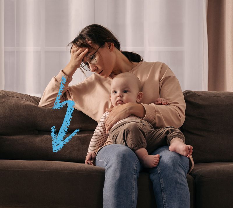Immagine correlata al testo mamma seduta sul divano con bambino in braccio ed espressione affaticata