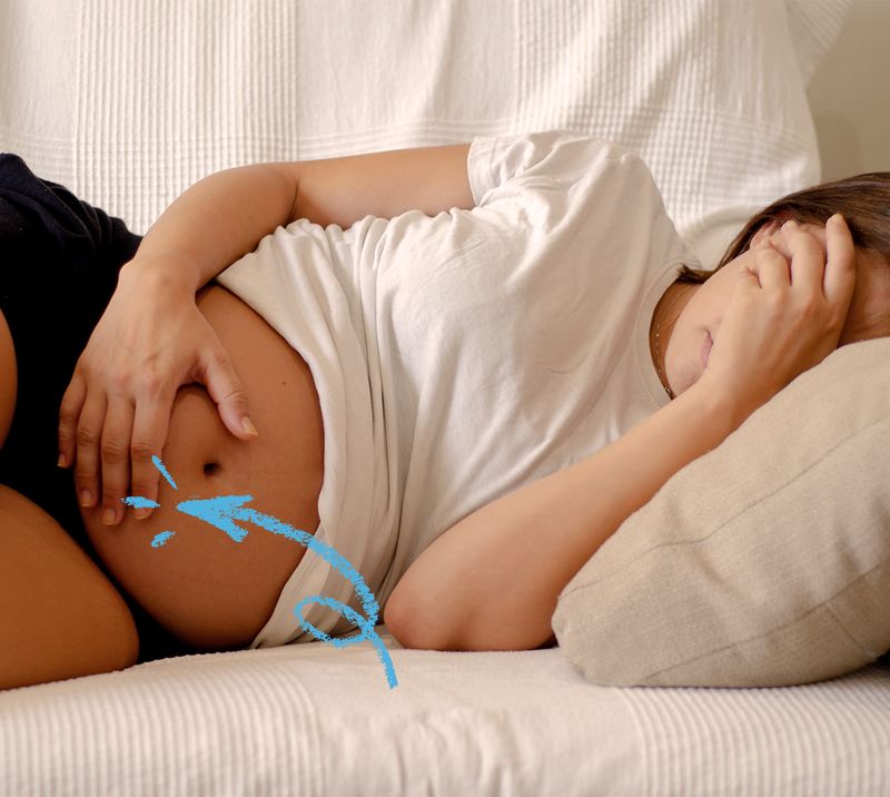 donna in gravidanza sdraiata con una mano davanti al viso