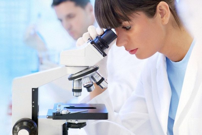 Immagine correlata al testo Ricercatrice che guarda al microscopio