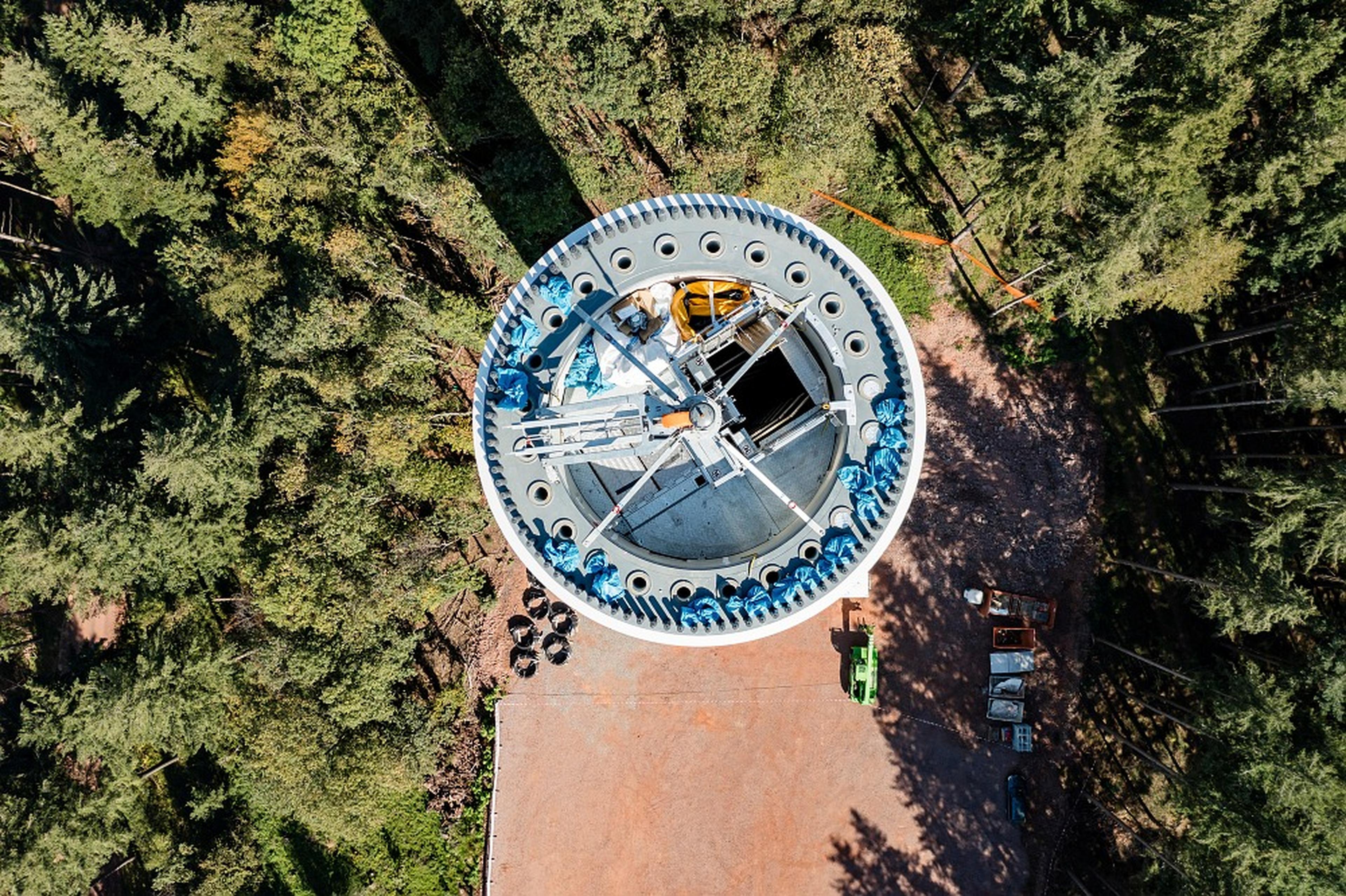 Offener Windradturm von oben, umgeben von Wald