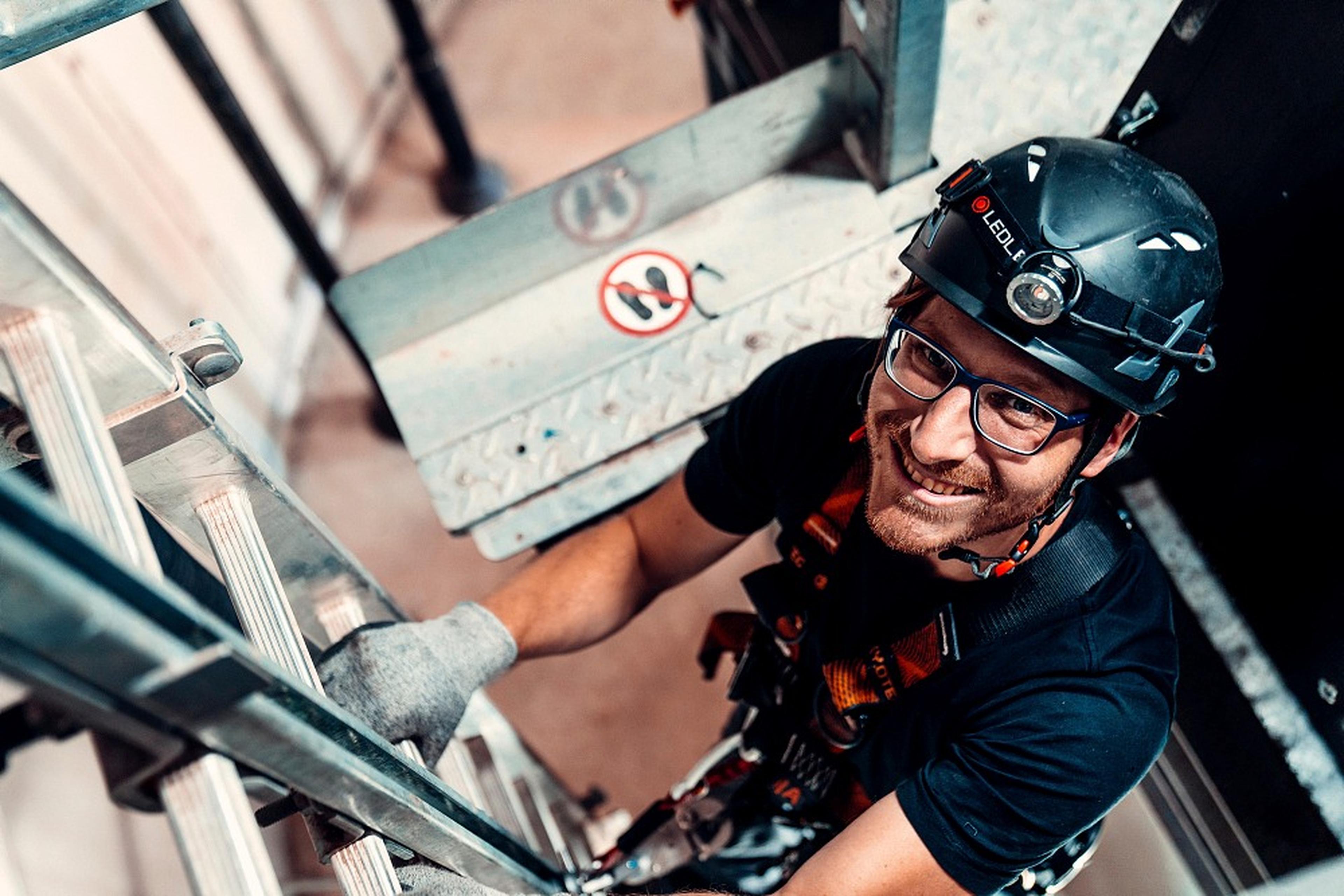 Techniker mit Helm auf Leiter in Windrad-Turm