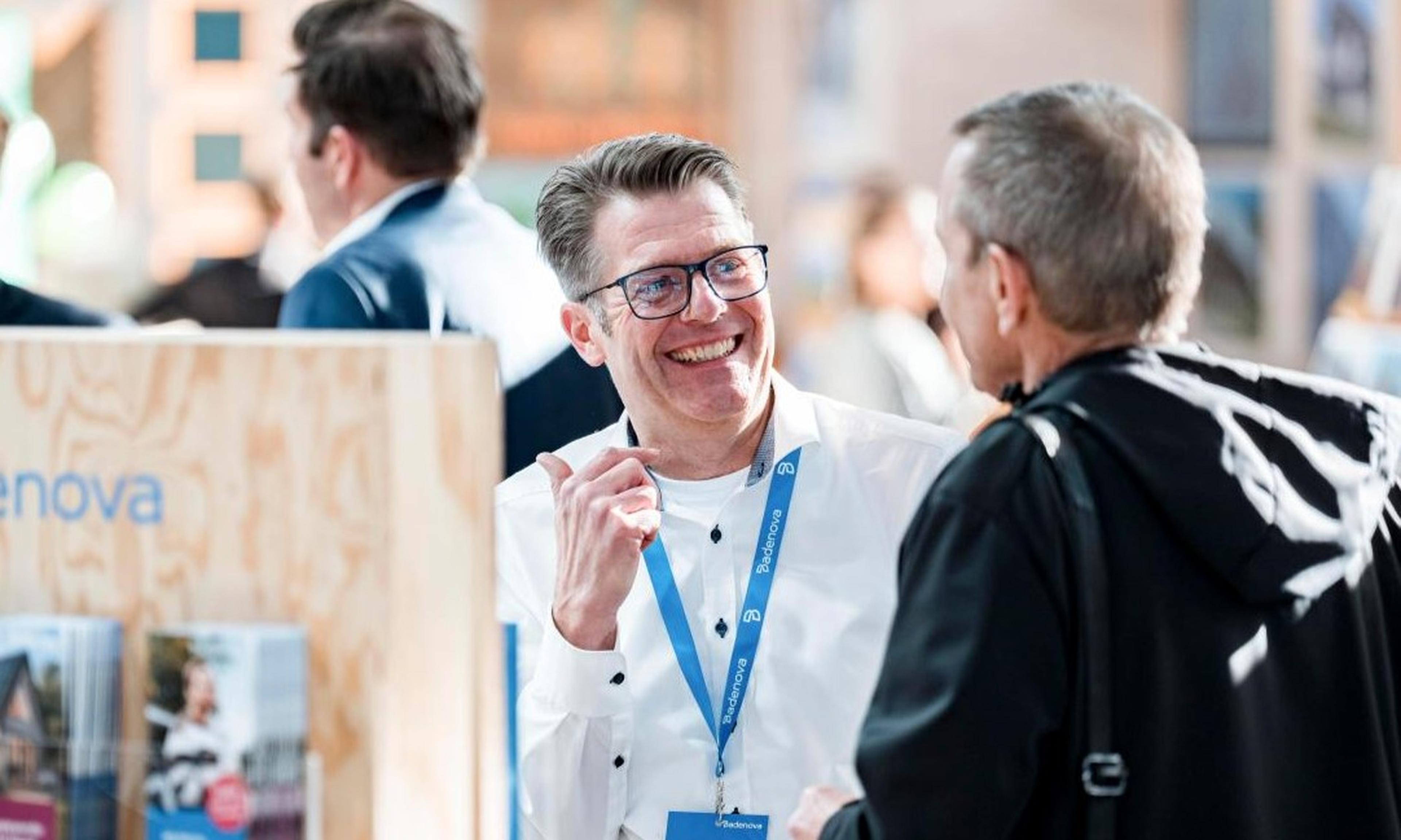Lachender Mitarbeiter im Gespraech am Badenova Messestand