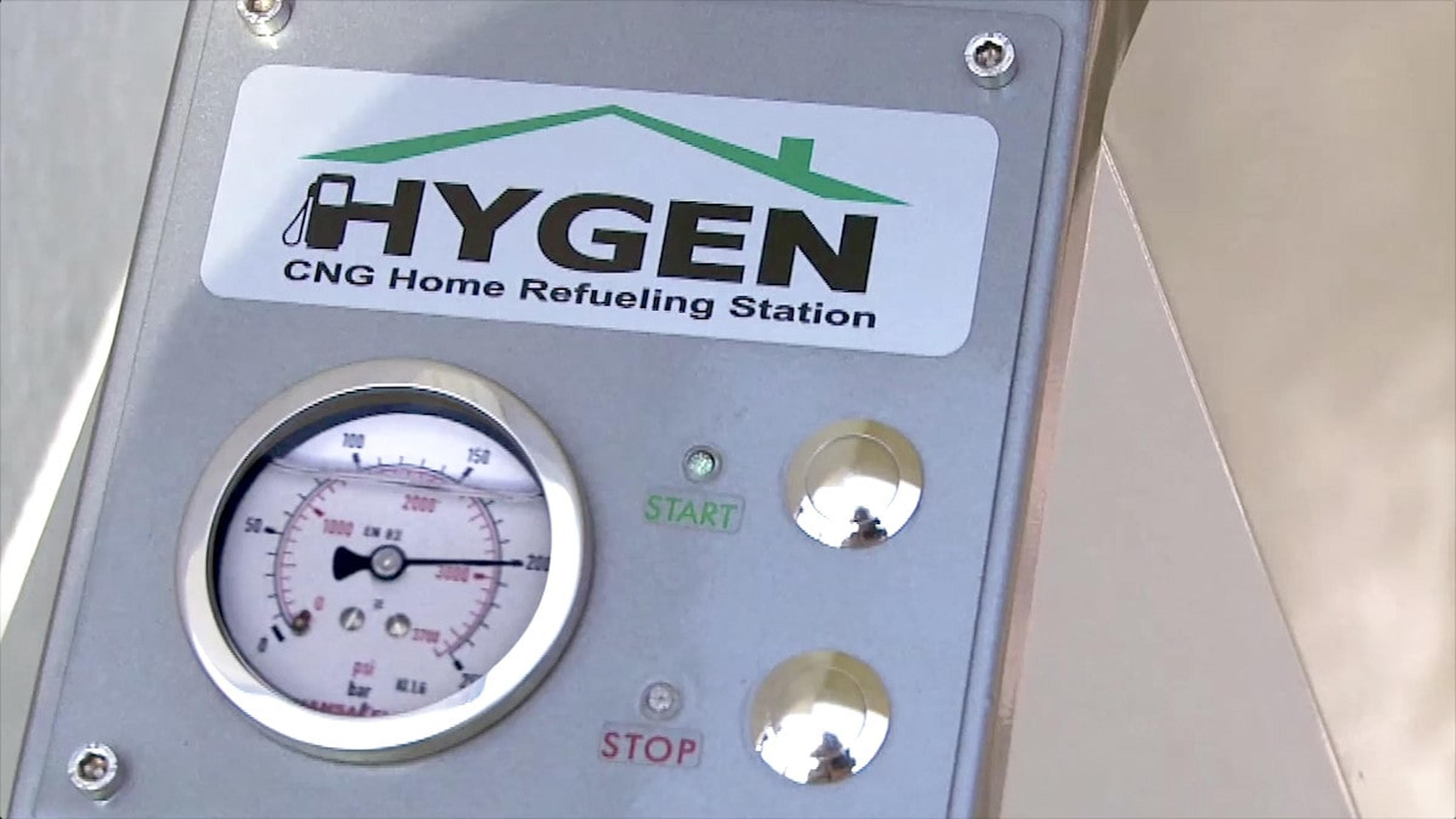 Nahaufnahme eines Bedienfelds einer Hygen-CNG-Heimtankstelle mit Manometer und Start- und Stopp-Tasten.