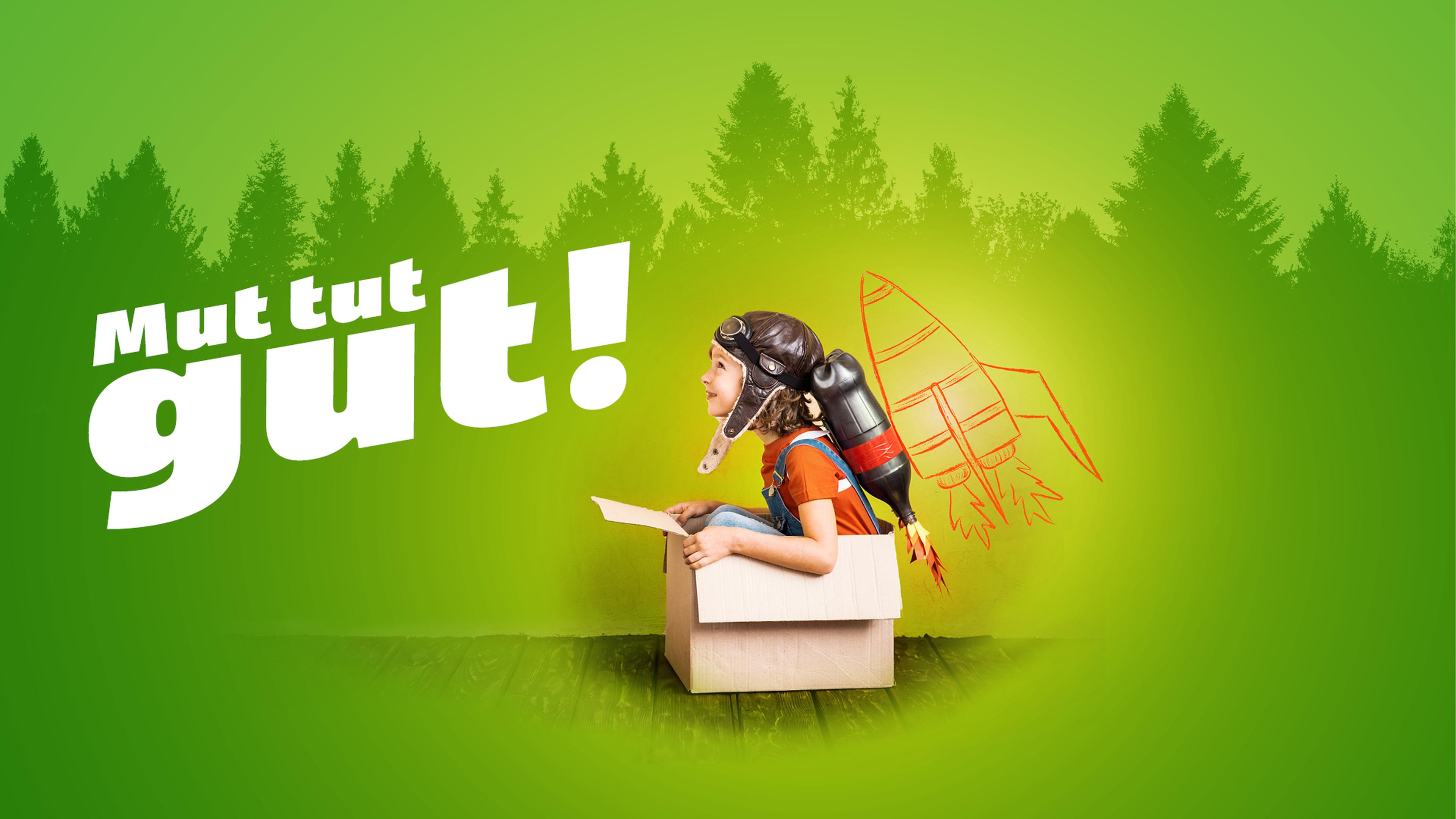Kind in einem Karton mit Helm und Raketenrucksack vor einem grünen Waldhintergrund. Der Text lautet „Mut tut gut!“.