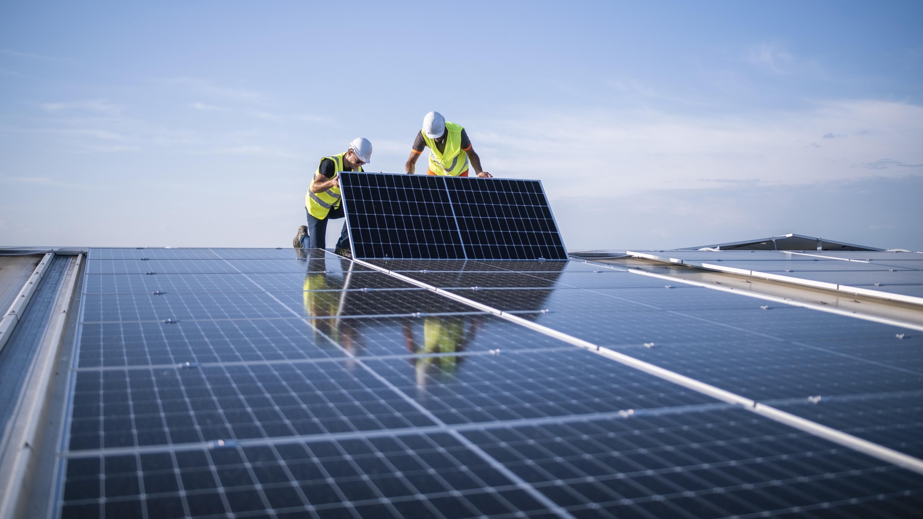 Installateure bringen ein PV-Modul an.