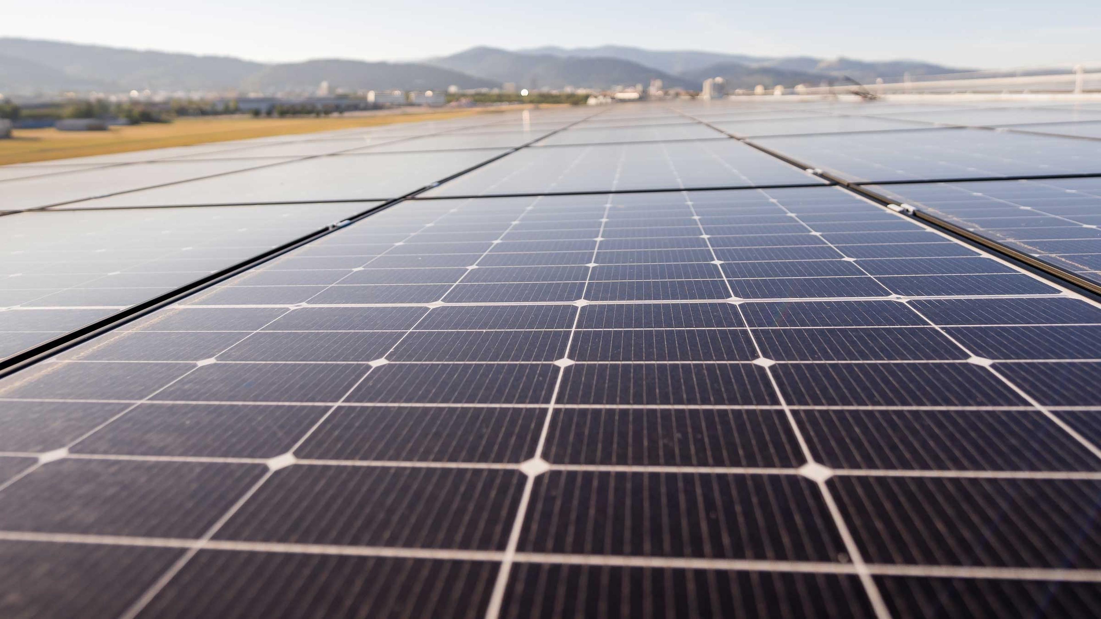 Photovoltaikanlage mit bergiger Landschaft im Hintergrund.
