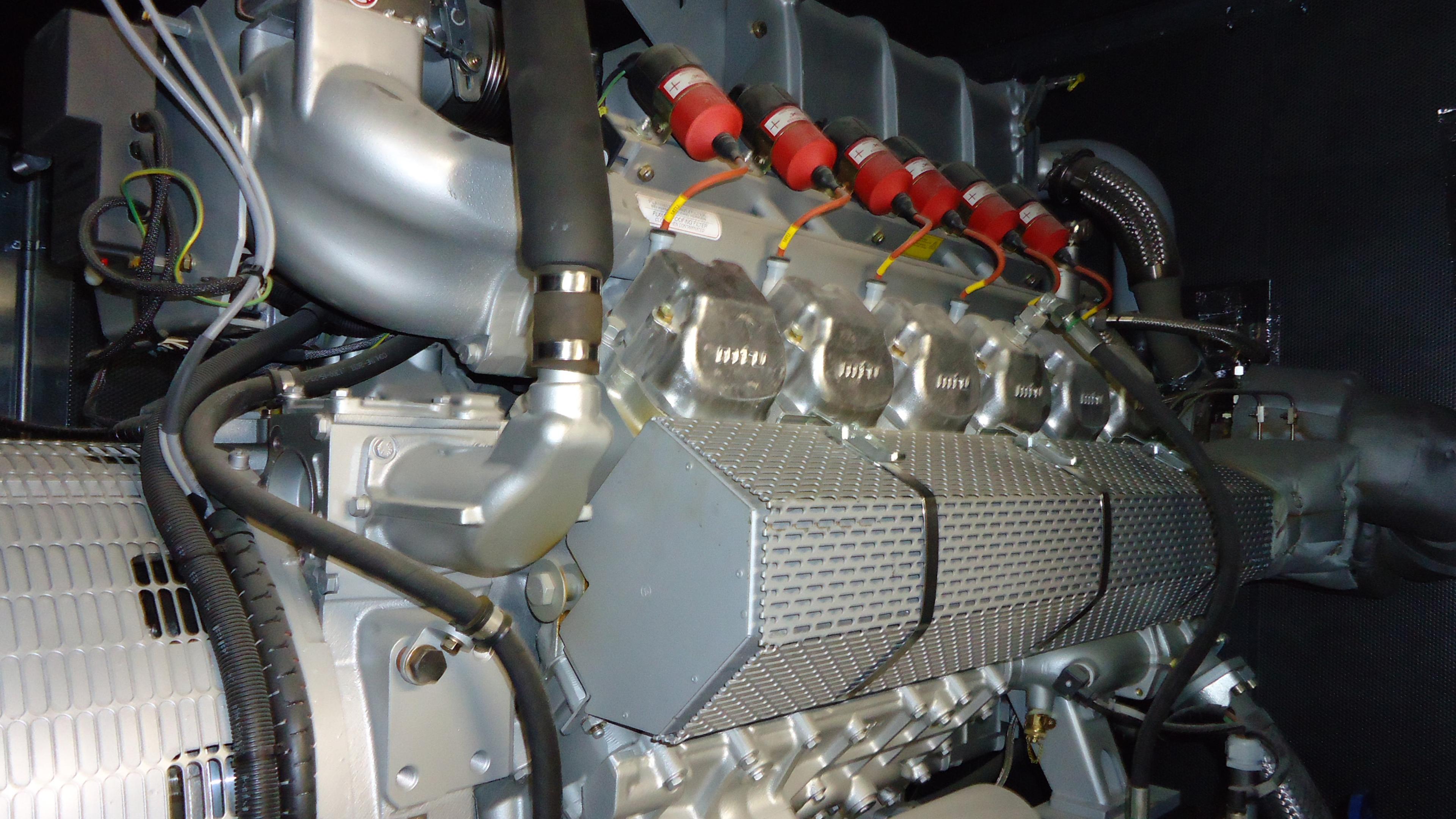Nahaufnahme eines metallischen Motors mit zahlreichen Rohren, Kabeln und roten elektrischen Bauteilen, die die komplexen mechanischen Details zeigen.