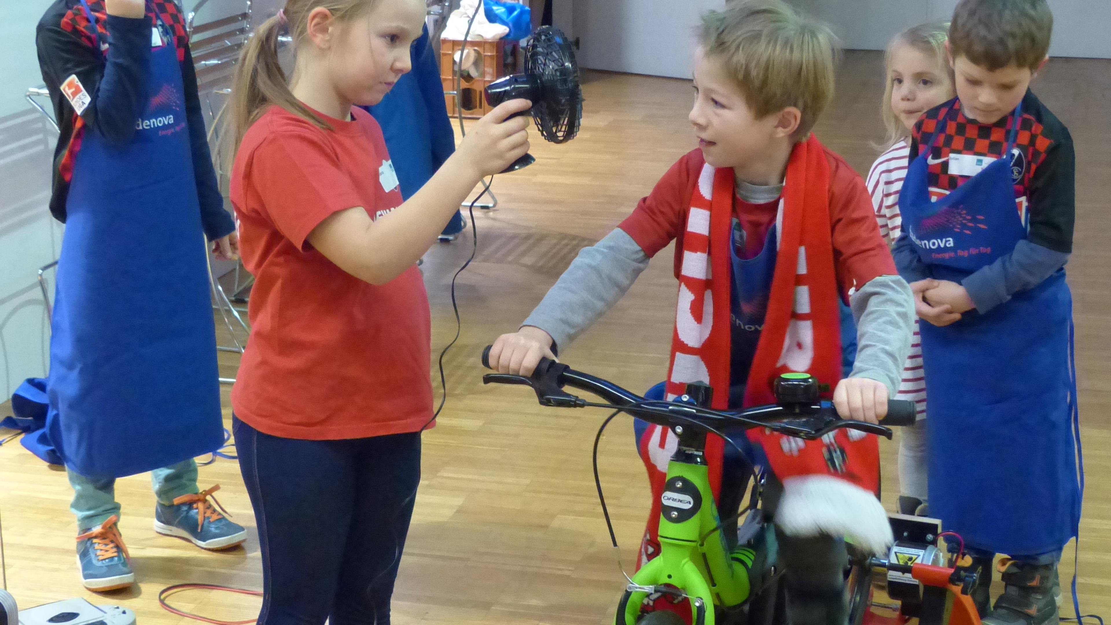 Ein Kind pedaliert auf dem Fahrrad und erzeugt so Energie, damit der Ventilator funktioniert