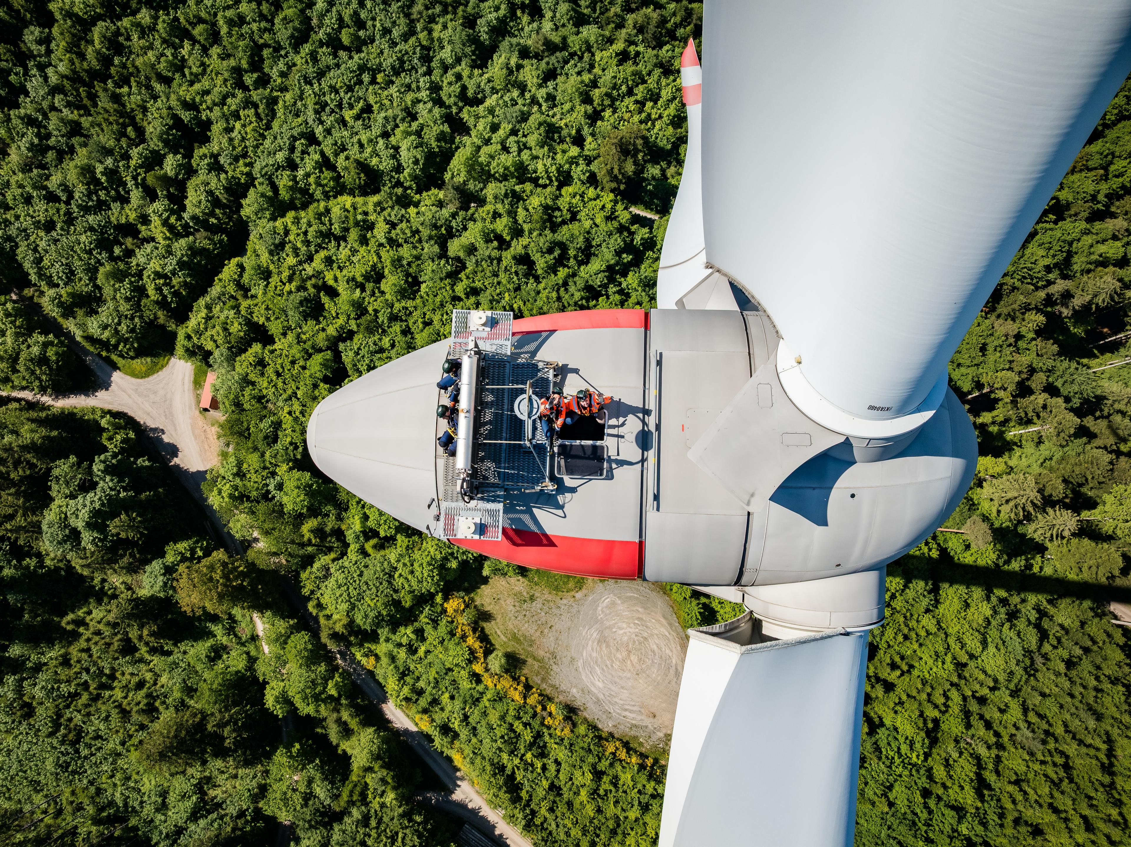 Windrad aus der Vogelperspektive, Techniker steht auf Windradturbine