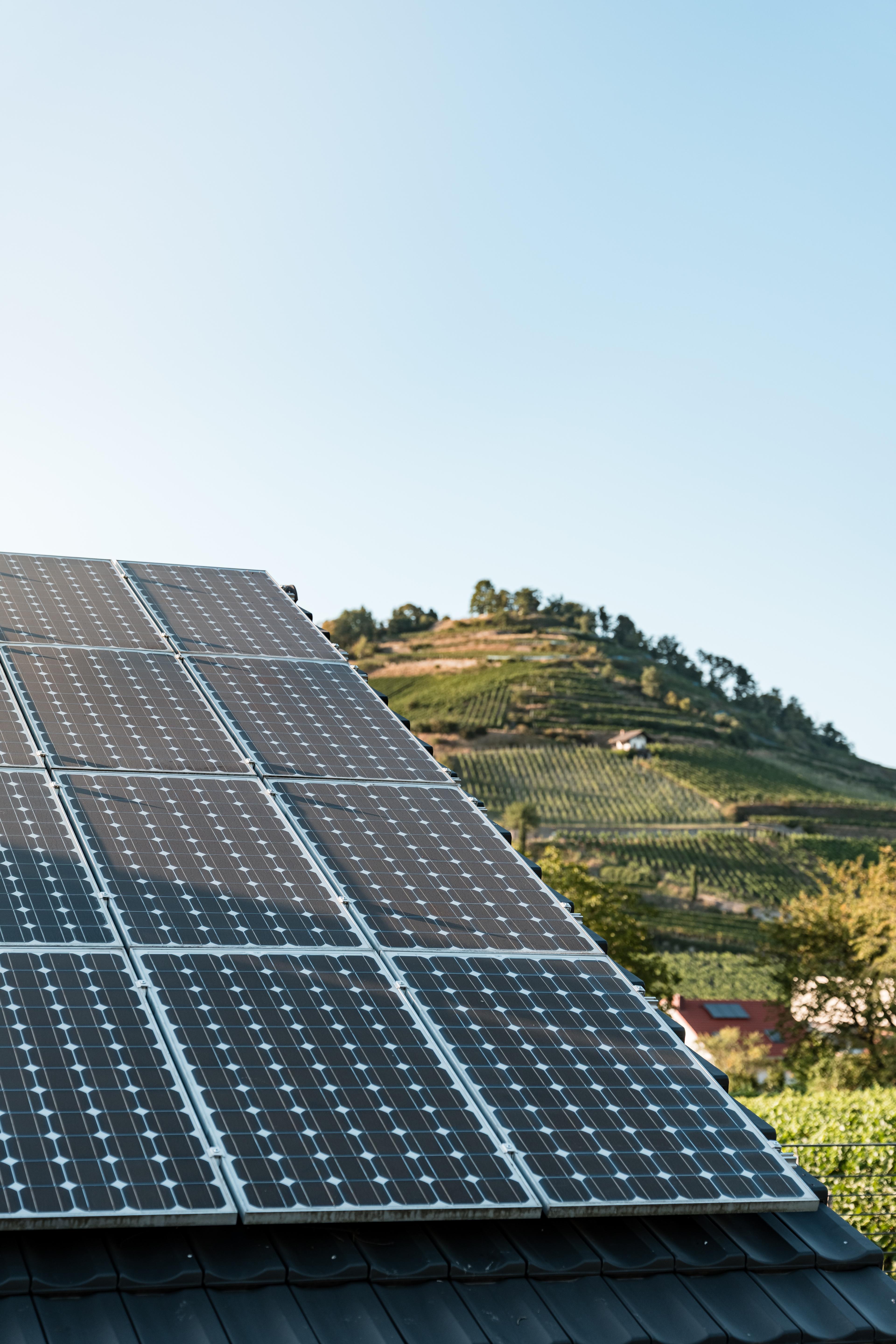 Photovoltaik auf Einfamilienhaus, im Hintergrund Berg mit Weinreben