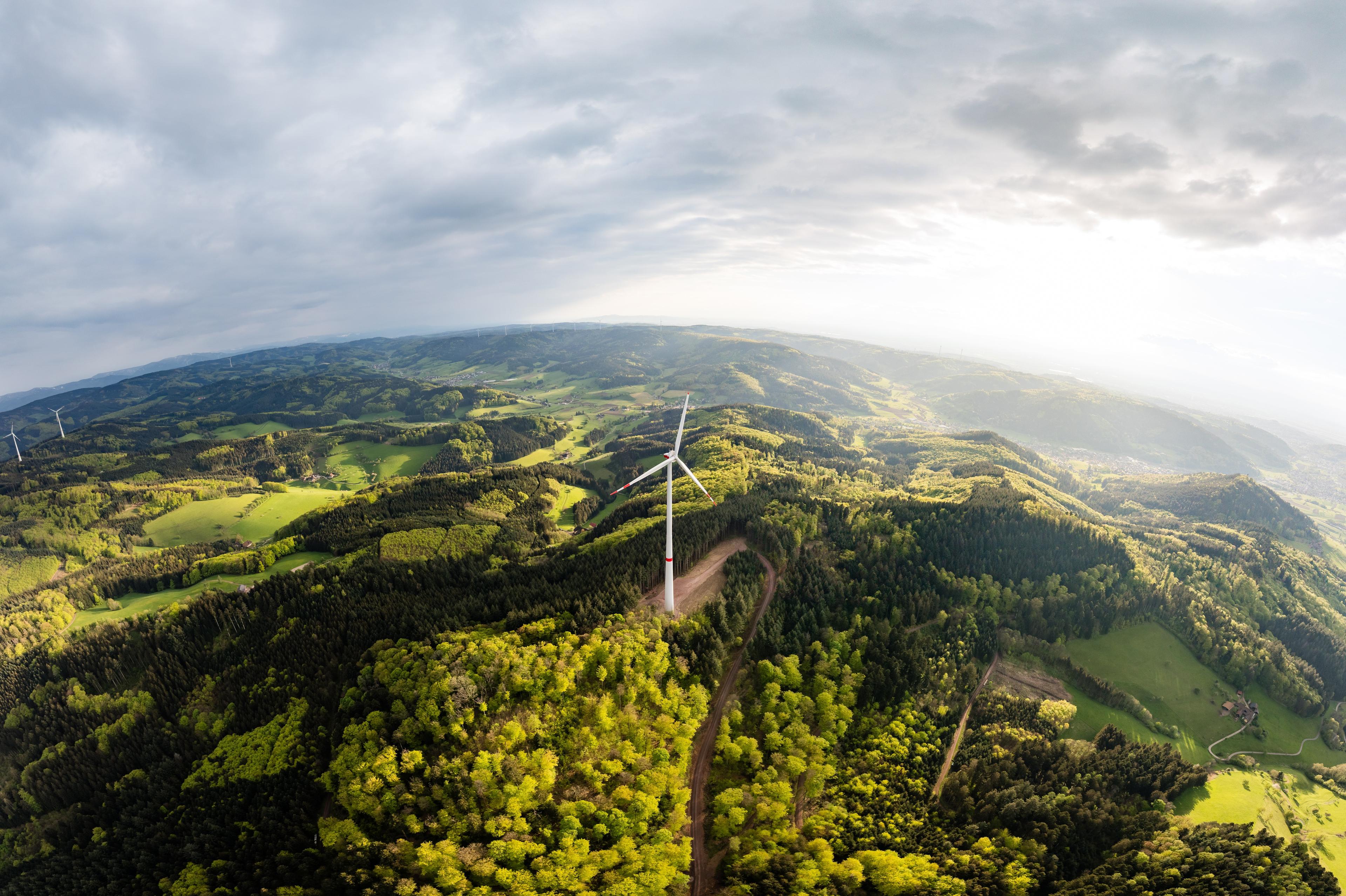 Panoramablick auf Windrad am Kallenwald und die Umgebung, grüne Wäder und bewölktem Himmel