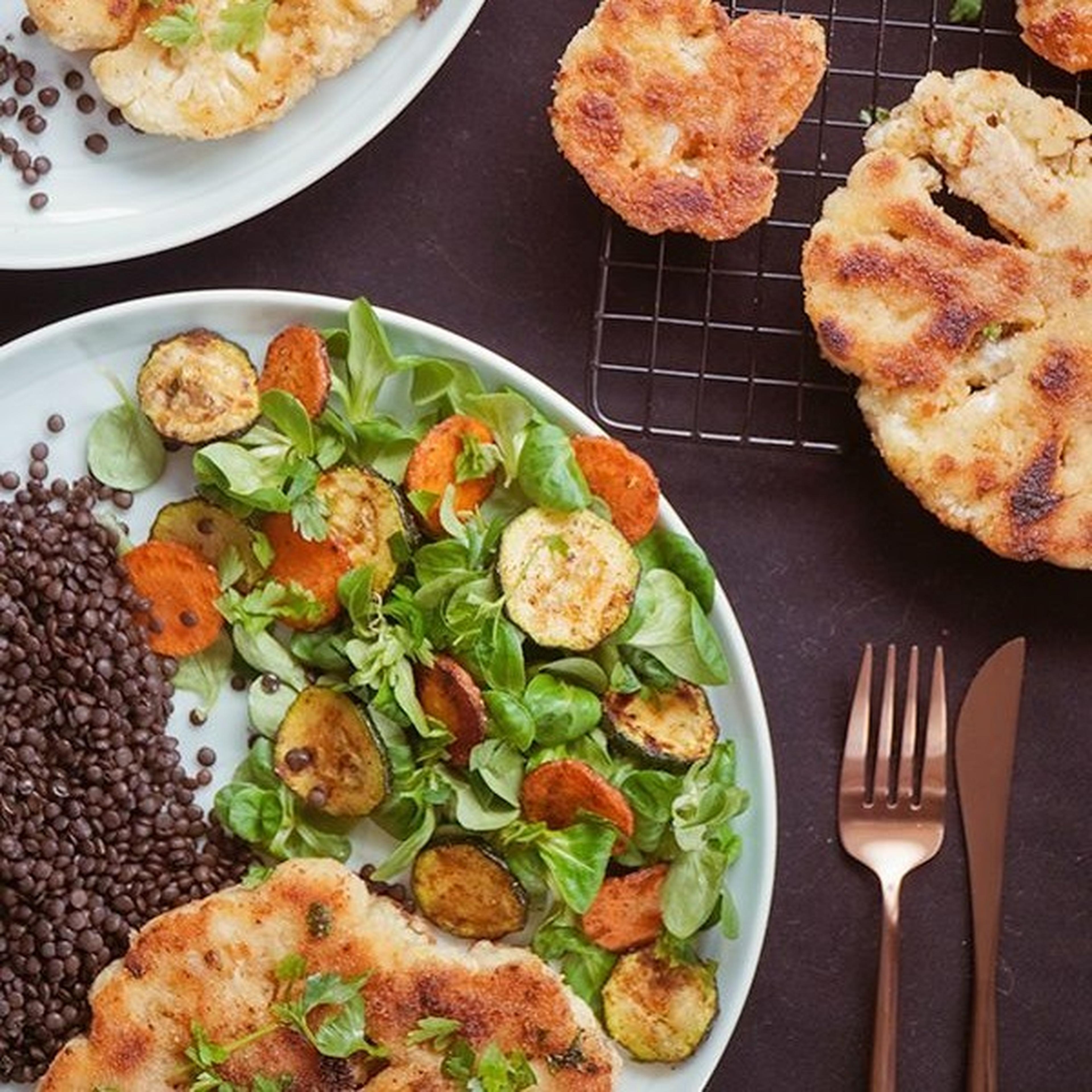 Veganes Gericht mit paniertem Blumenkohl, Linsen und gebratenem Gemüse.