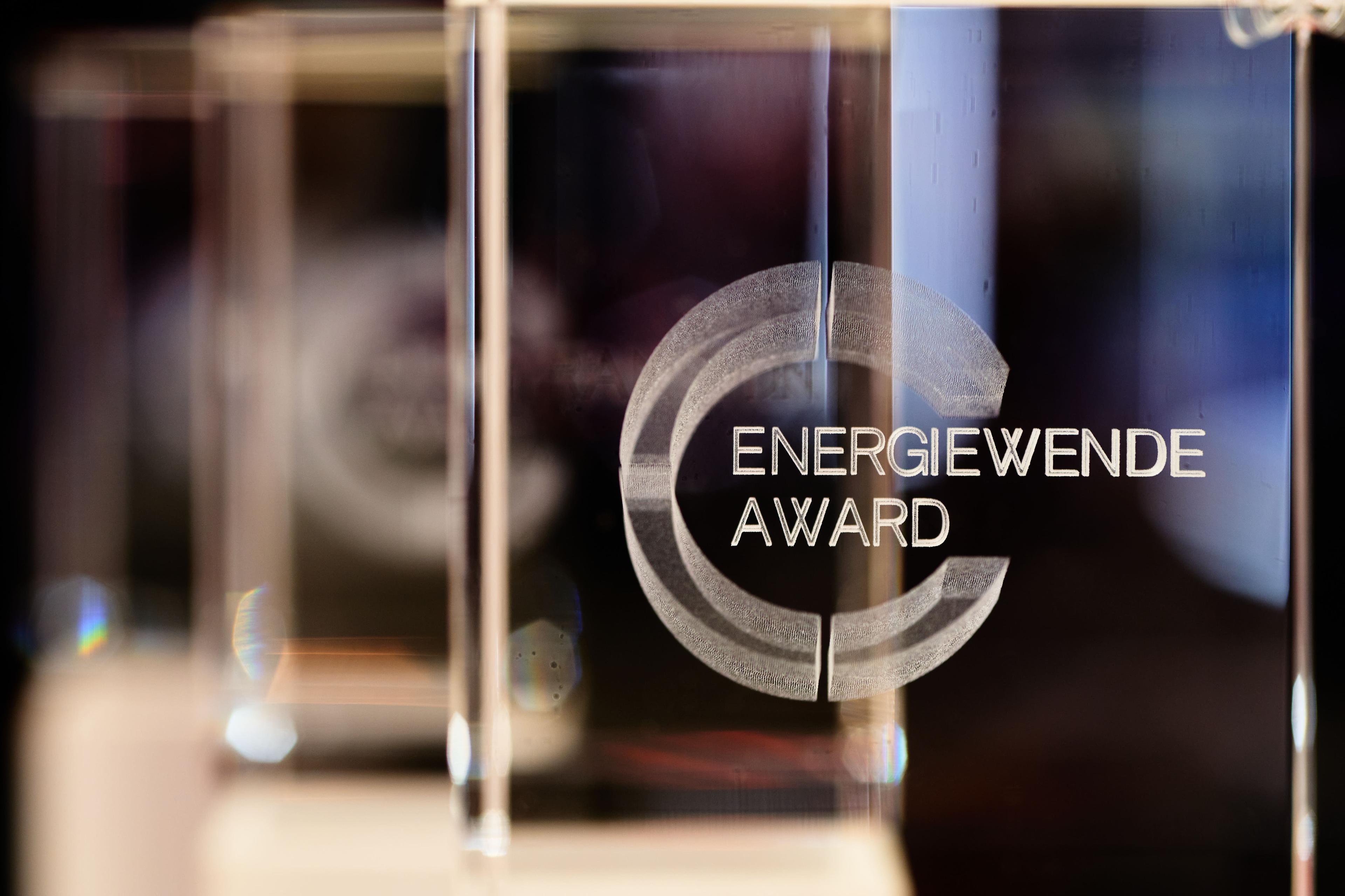Nahaufnahme einer Glastrophäe mit der Aufschrift „Energiewende Award“; der unscharfe Hintergrund hebt die polierte Oberfläche hervor.