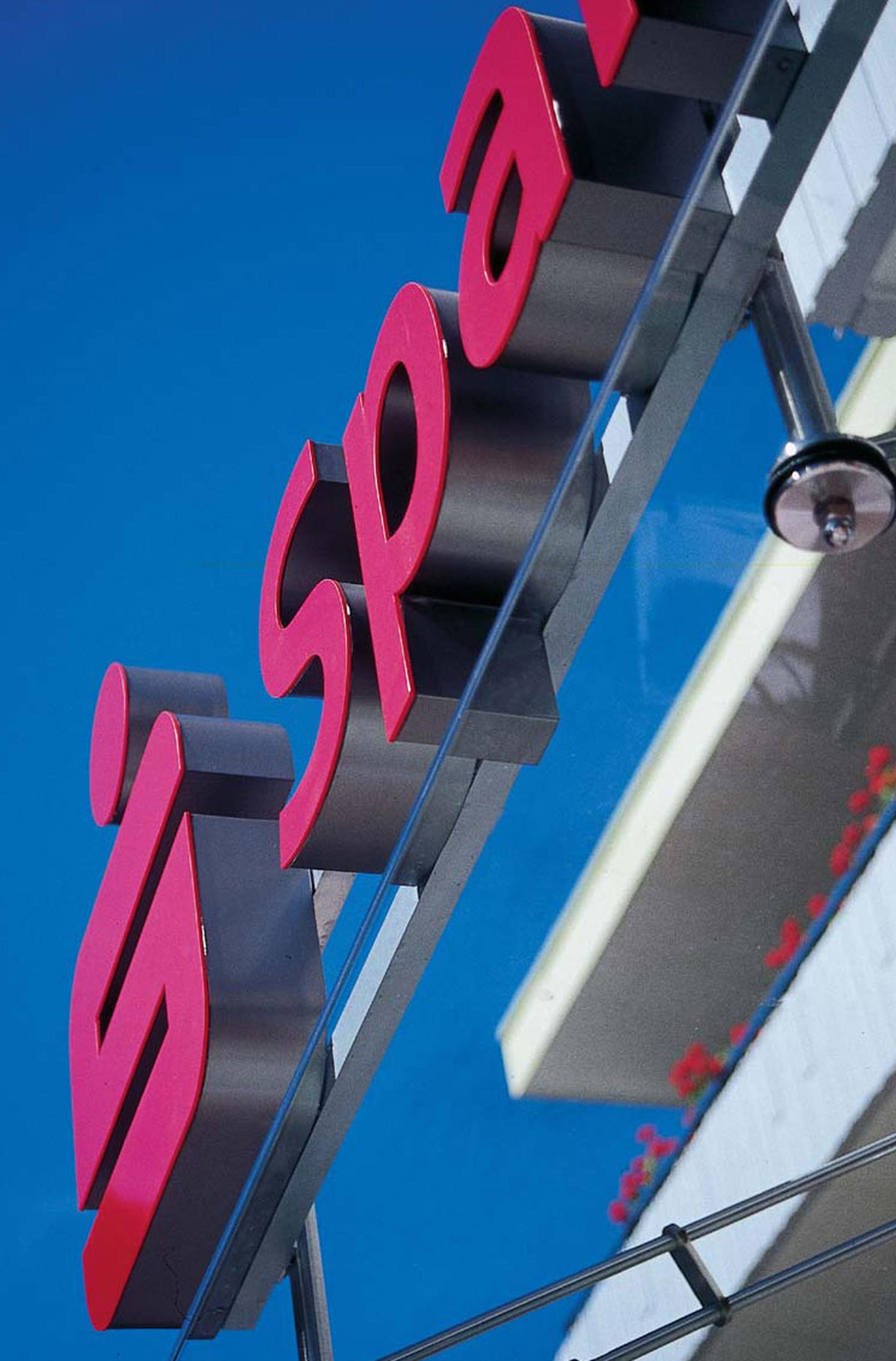Nahaufnahme eines rot-grauen „Sparkasse“-Schilds vor blauem Himmel, das mit Metallhalterungen an einem Gebäude befestigt ist.