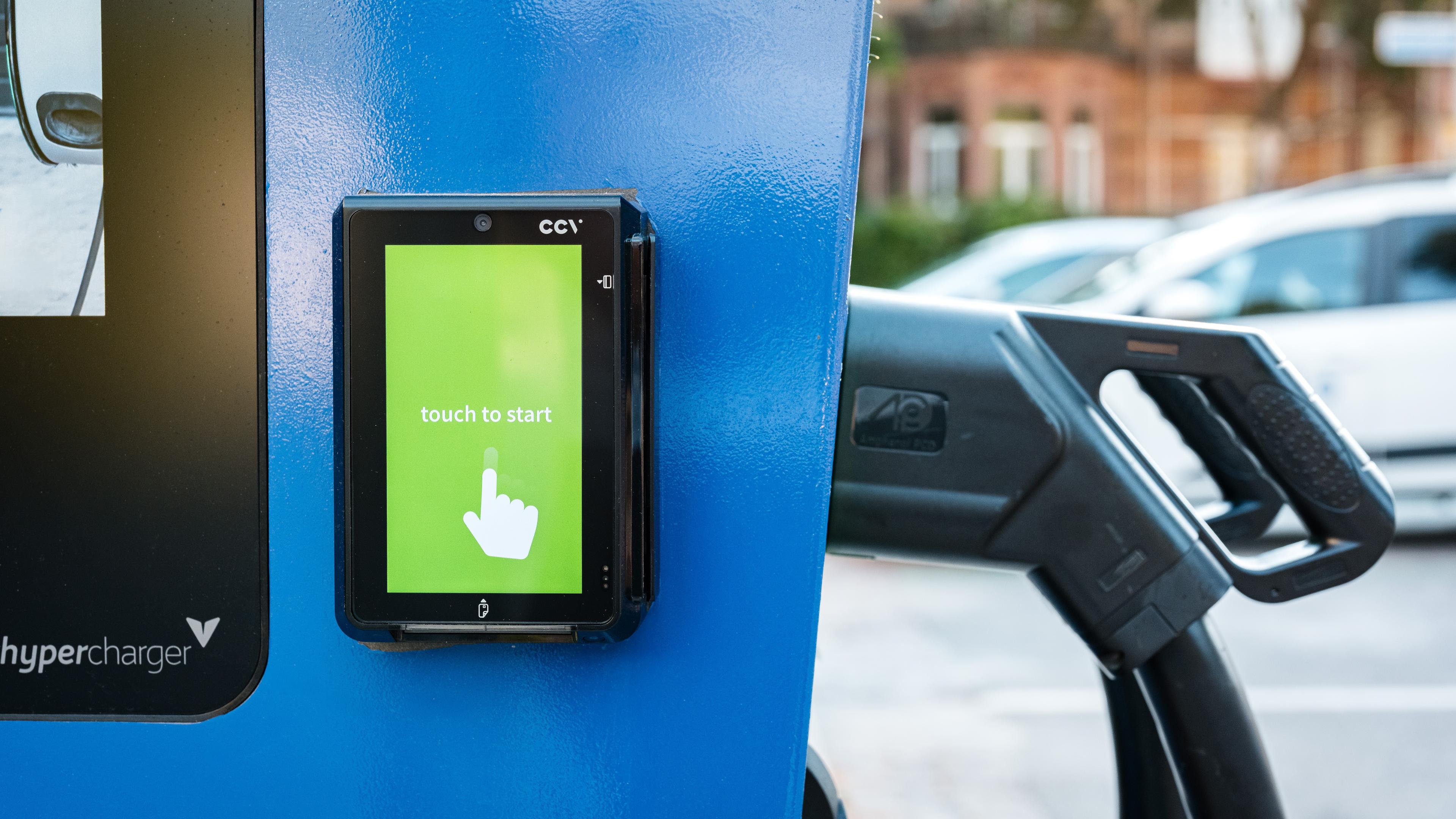 Ausschnitt einer Schnellladestation mit Bezahlterminal auf Höhe des Displays und der Ladestecker.