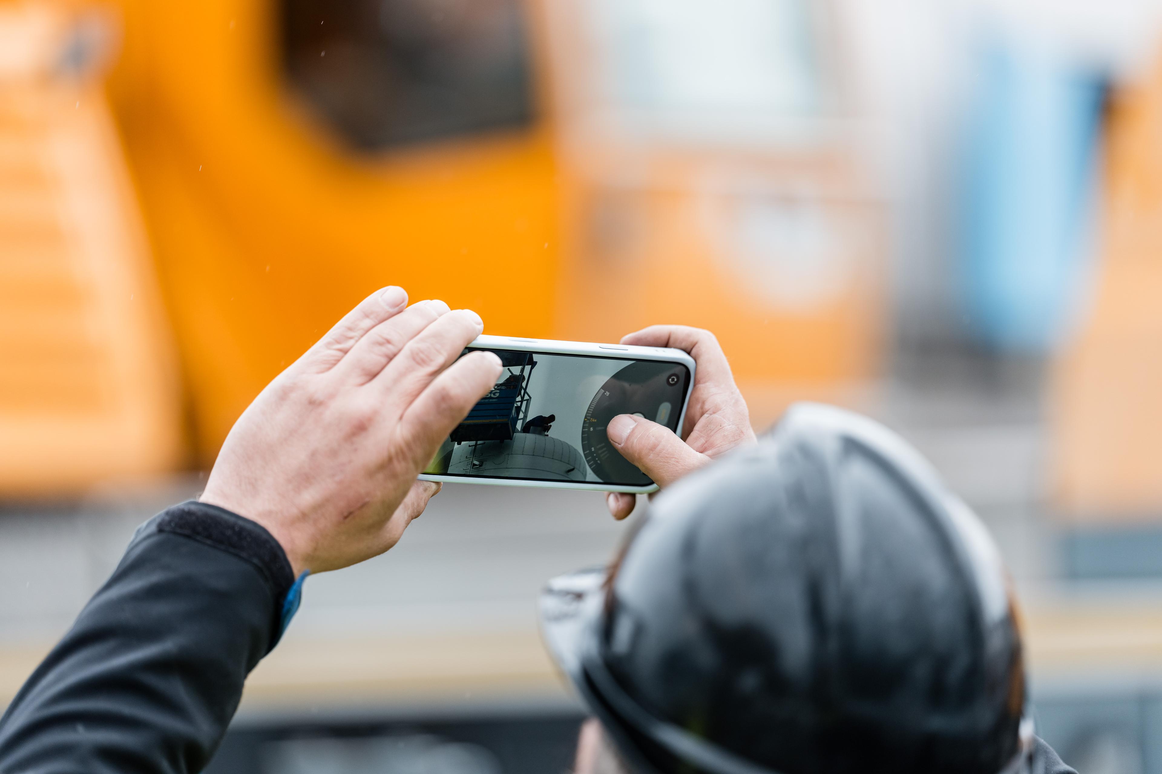 Badenova Mitarbeiter fotografiert einen Kollegen auf einer Wärmeanlage vor einem Baustellenfahrzeug