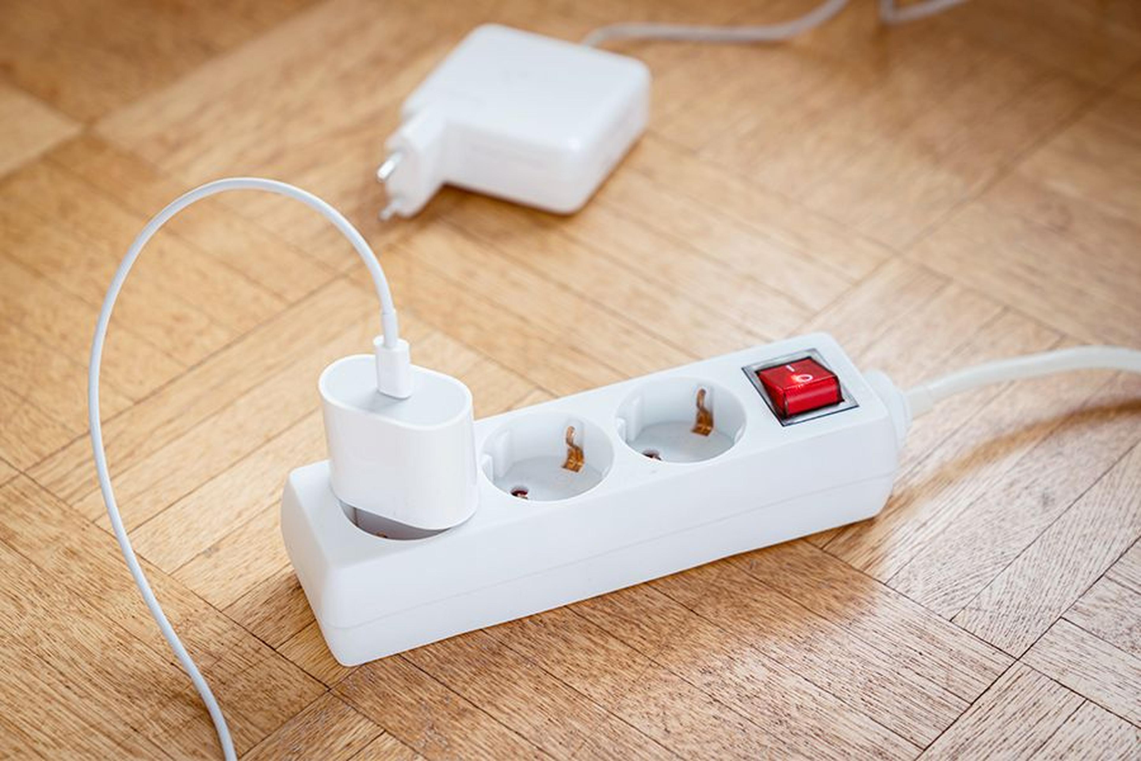 Mehrfachsteckdose mit Kippschalter und angeschlossenem Netzteil auf Holzboden