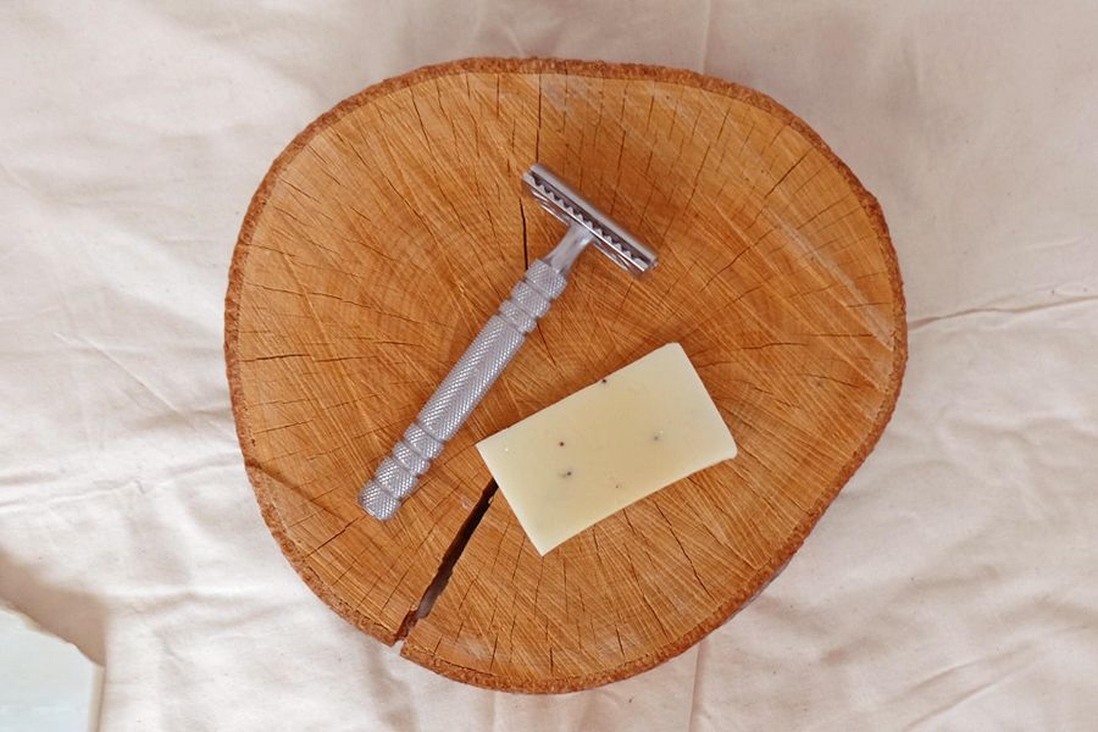 Metallrasierer und feste Seife auf einer Holzscheibe