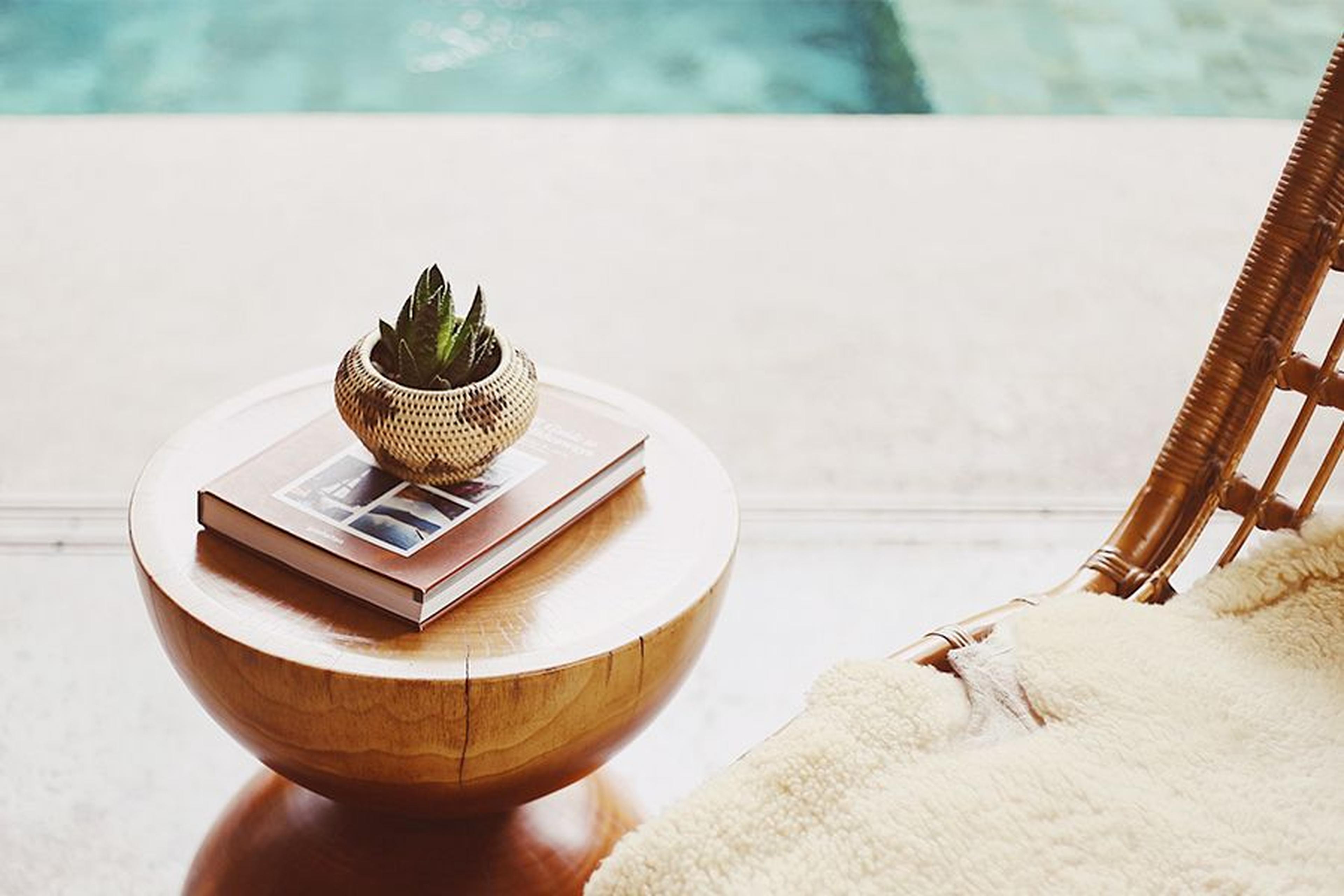 Beistelltisch mit Buch und Zimmerpflanze neben einem Rattanstuhl