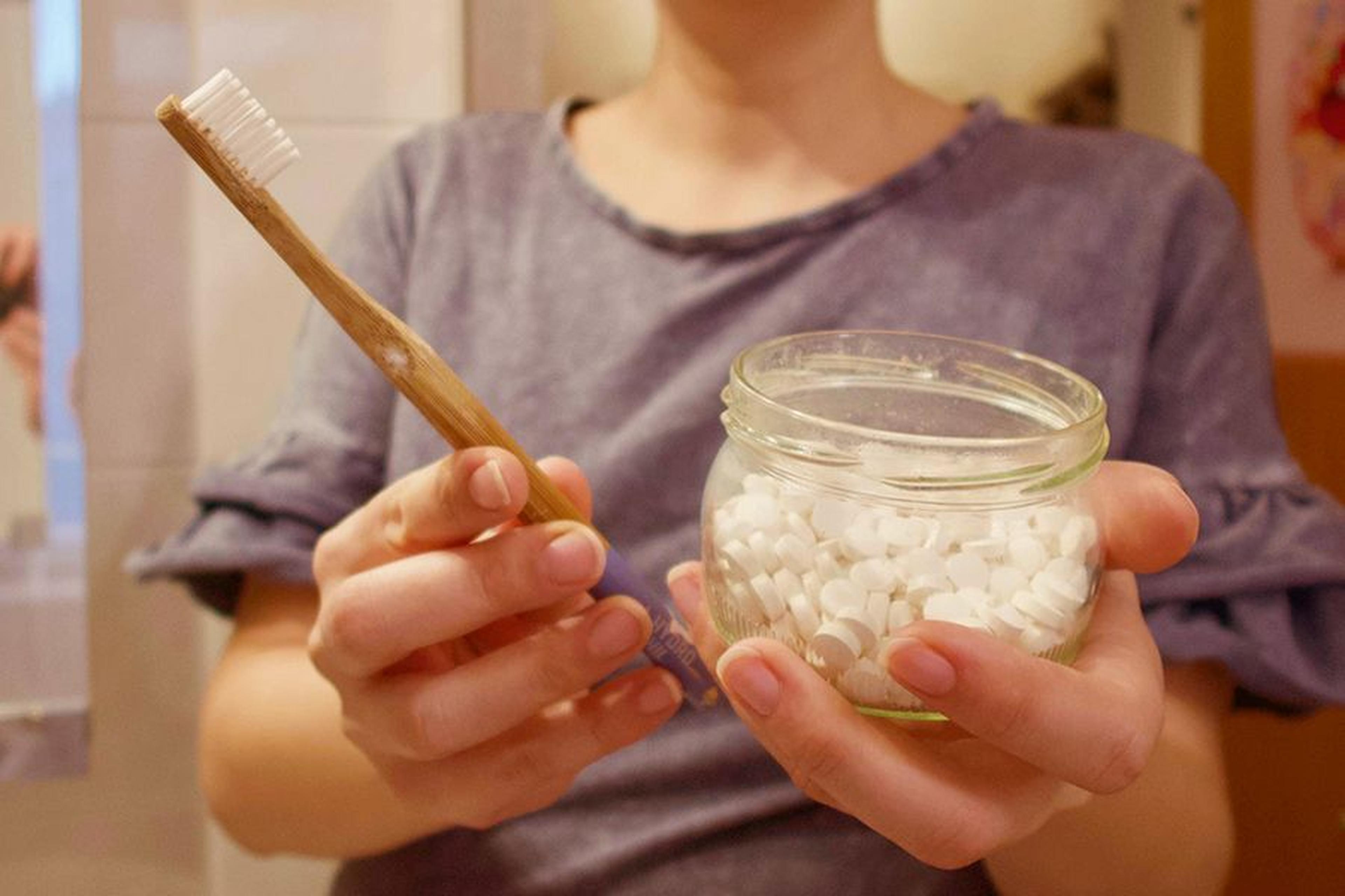 Holzzahnbürste und plastikfreie Zahnpflege-Tabs in einem Glas