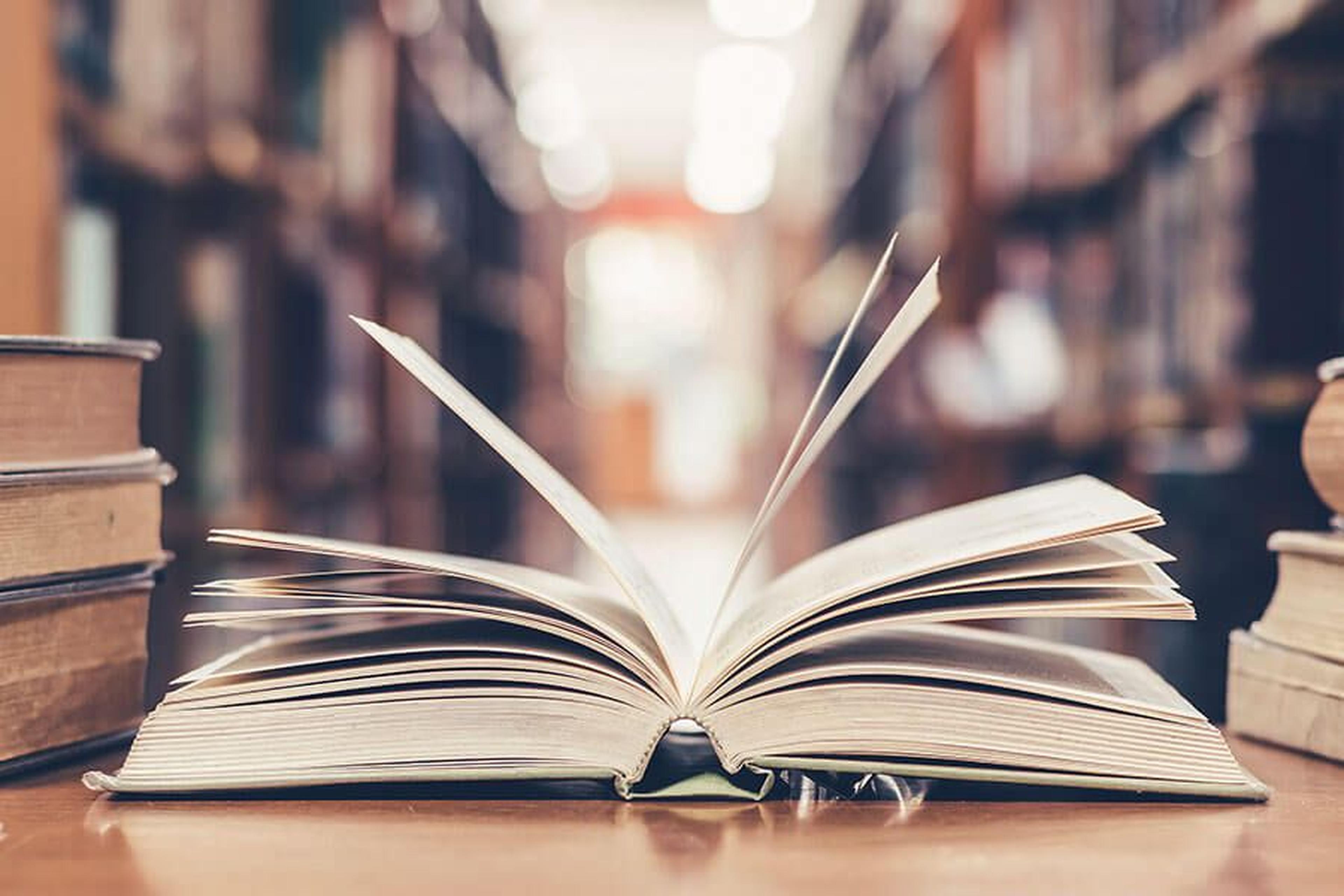 Aufgeschlagenes Buch liegt auf einem Tisch in einer Bibliothek.