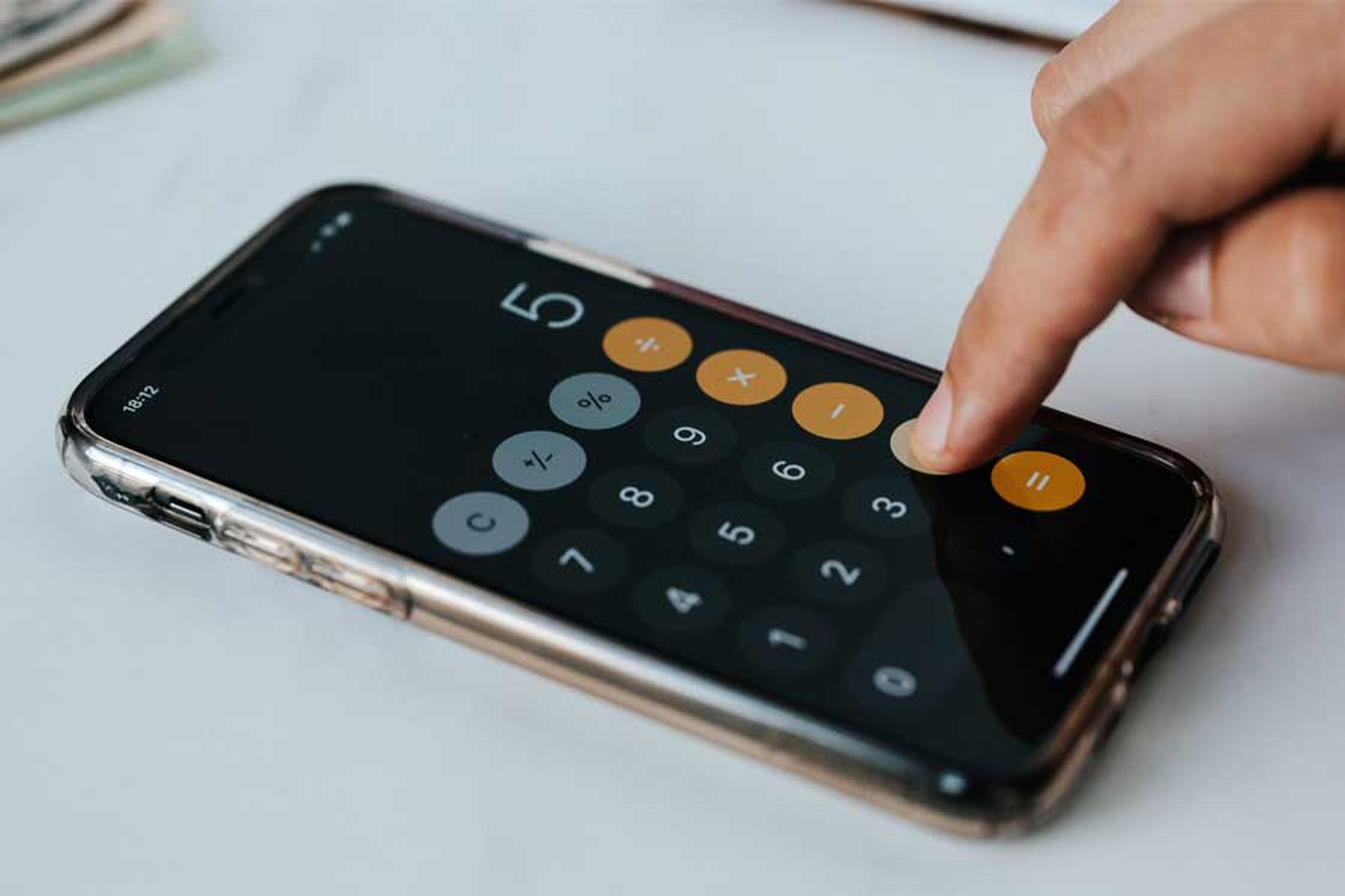 Finger bedient Taschenrechner auf dem Smartphone