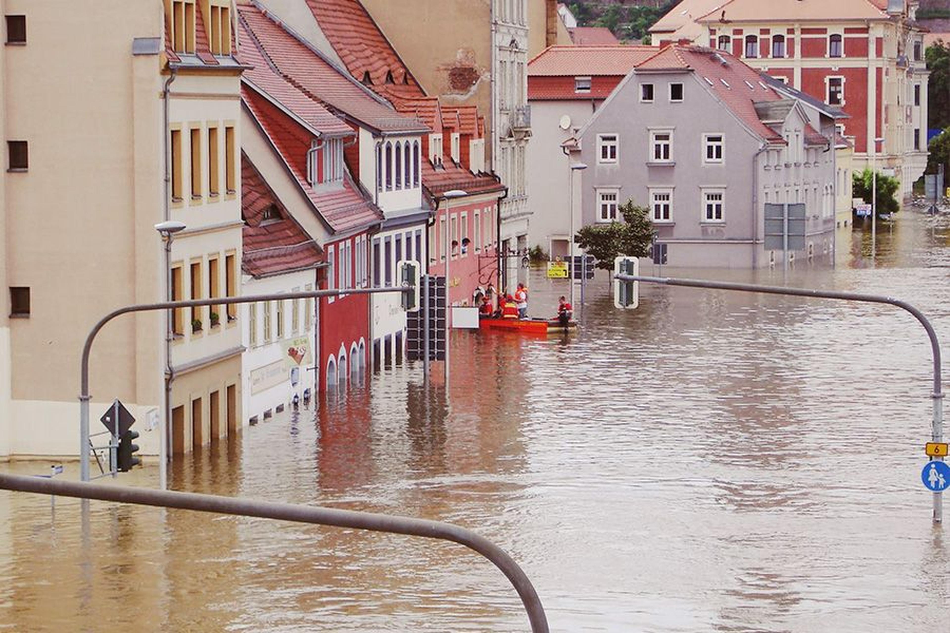 Überflutete Stadtstraße mit Rettungskräften in einem Boot.