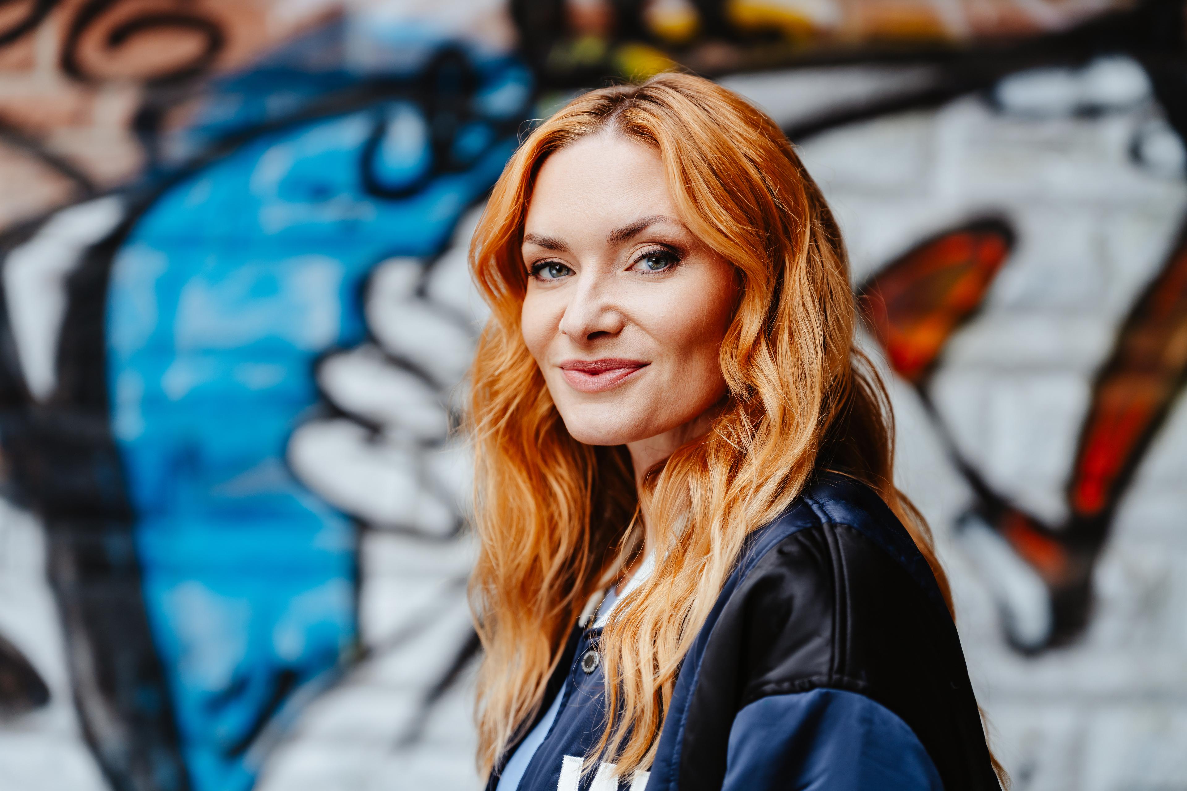 Frau steht in Freiburg vor einem Grafiti und schaut in die Kamera