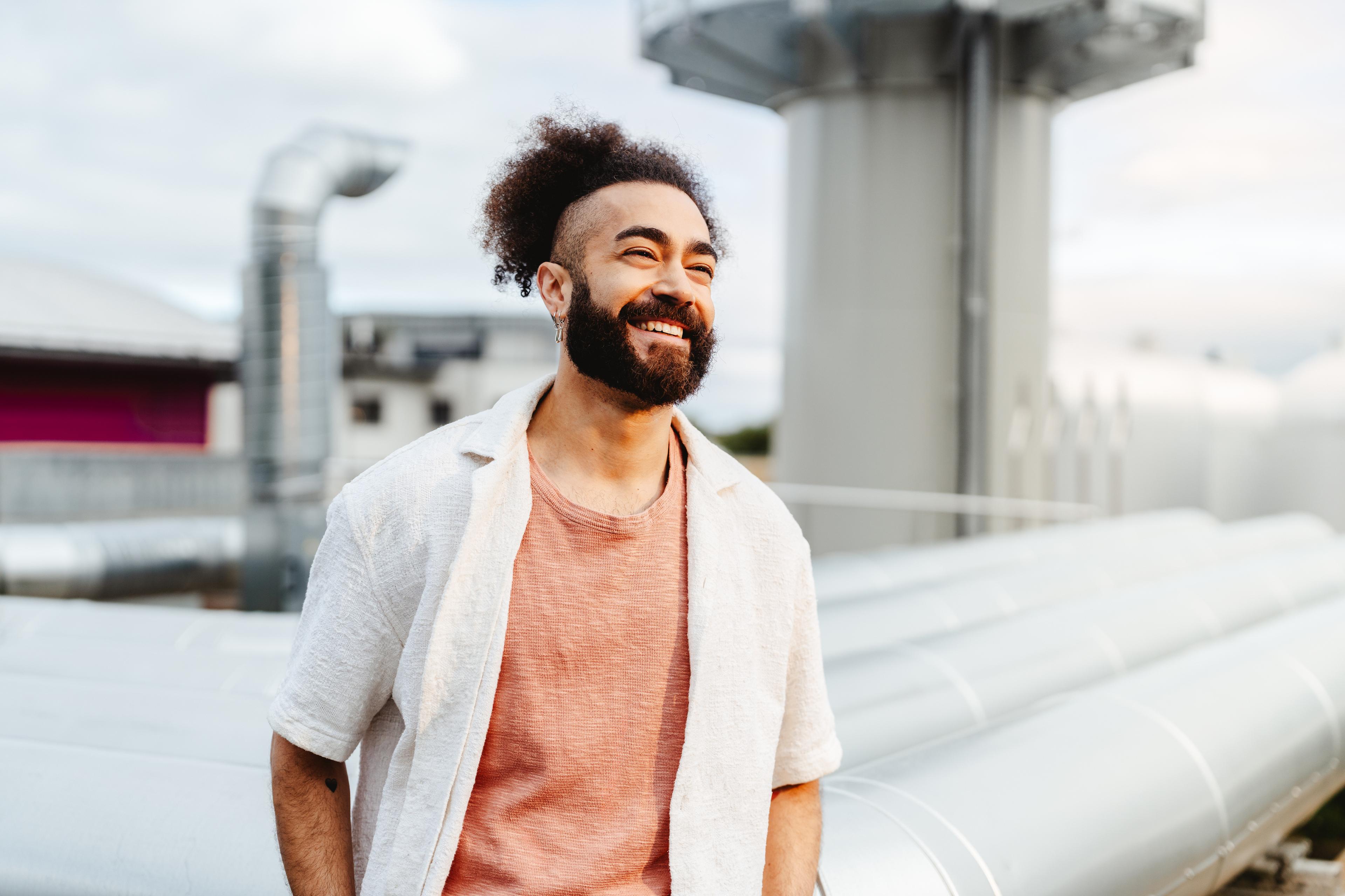 Mann steht lächelnd vor Rohren und schaut in die ferne