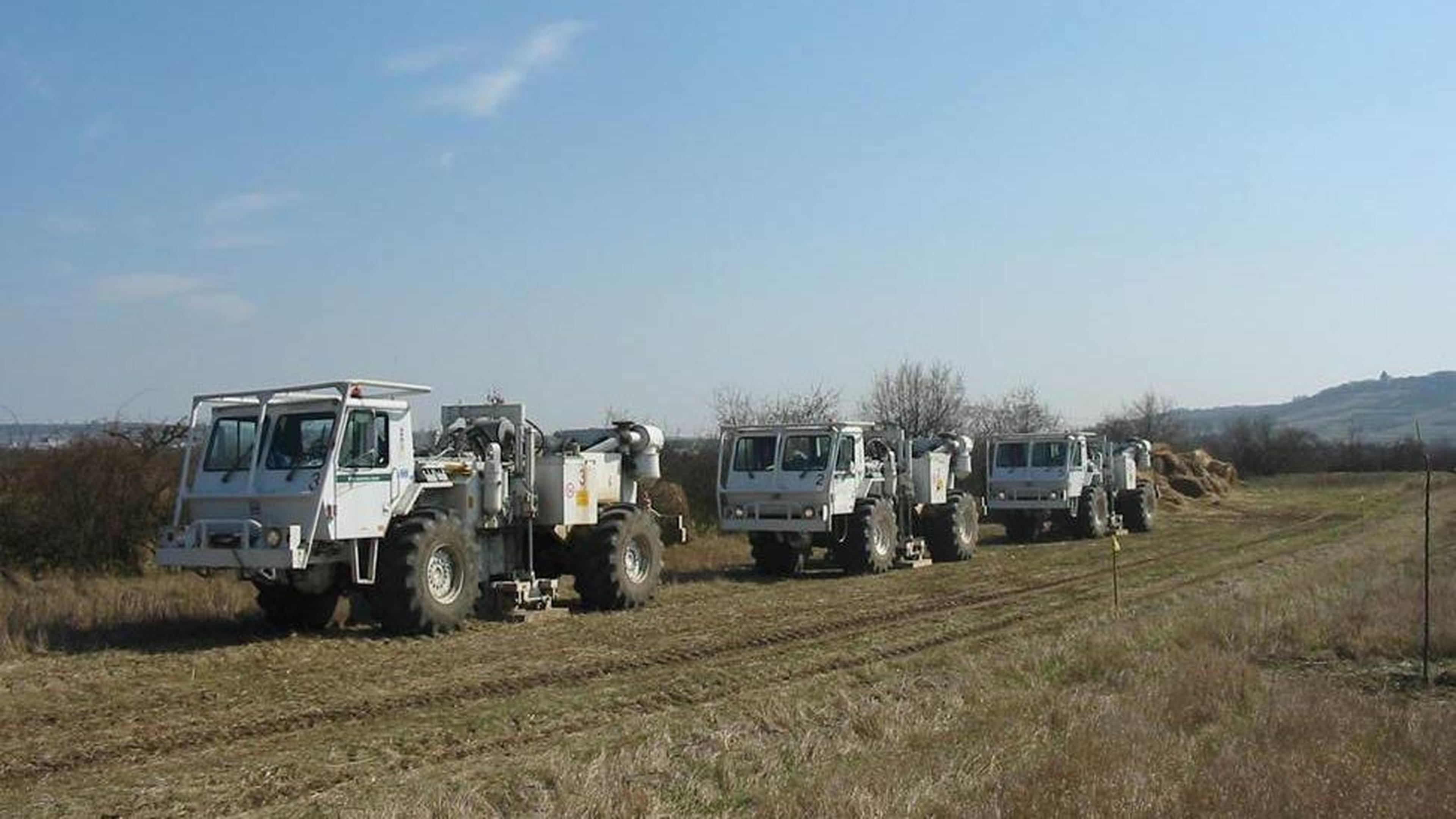 Vier weiße Rüttelwagen standen unter strahlend blauem Himmel auf einem trockenen, grasbewachsenen Feld.