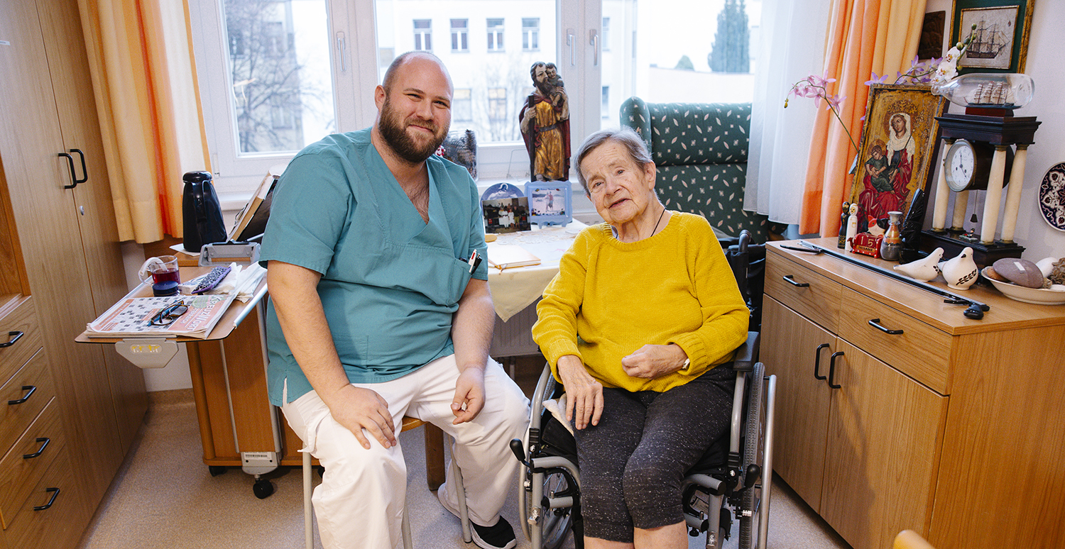 Pfleger in grüner Arbeitskleidung lächelnd