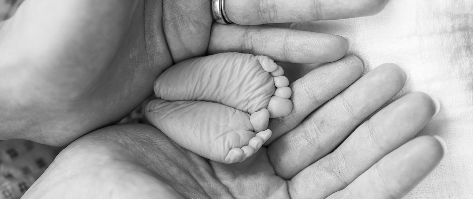 schwarz-weißes Foto mit Babyfüßen in Händen