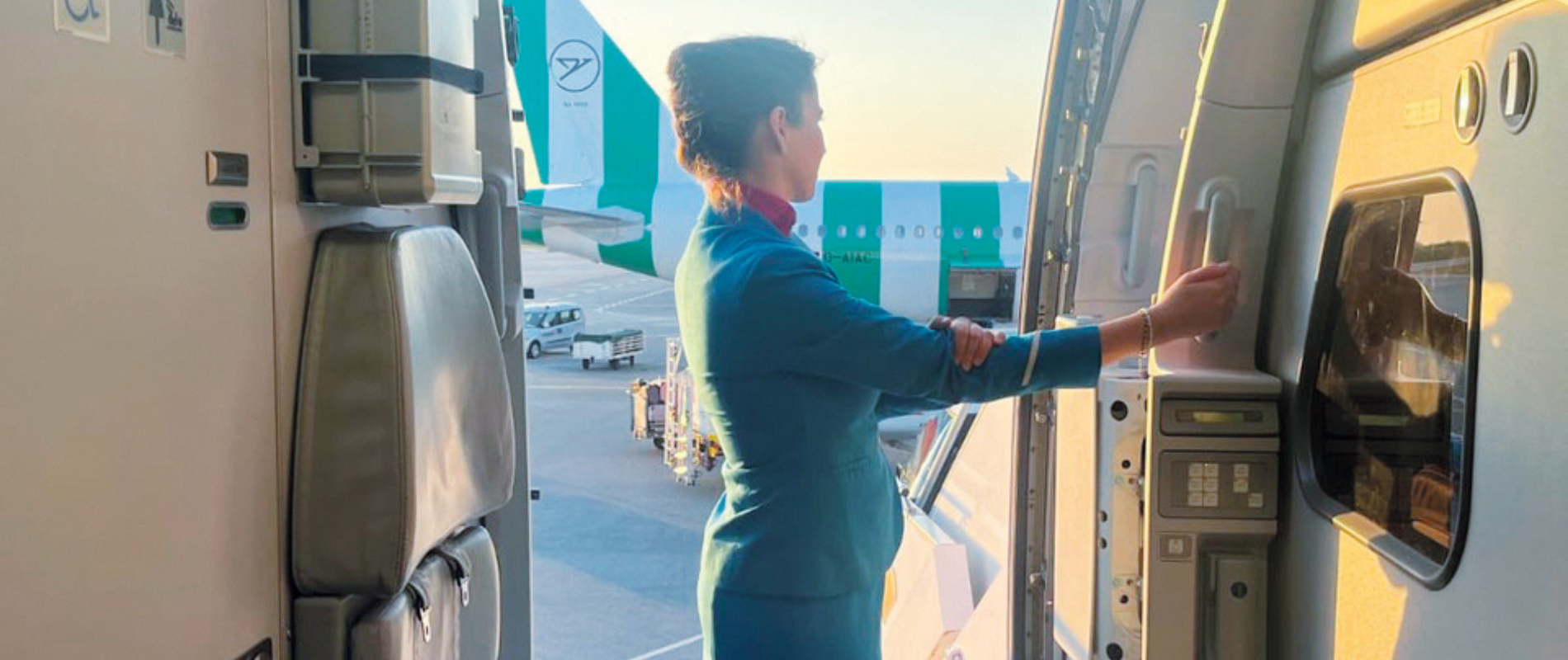 Flugbegleiterin steht in geöffneter Tür eines Flugzeuges.