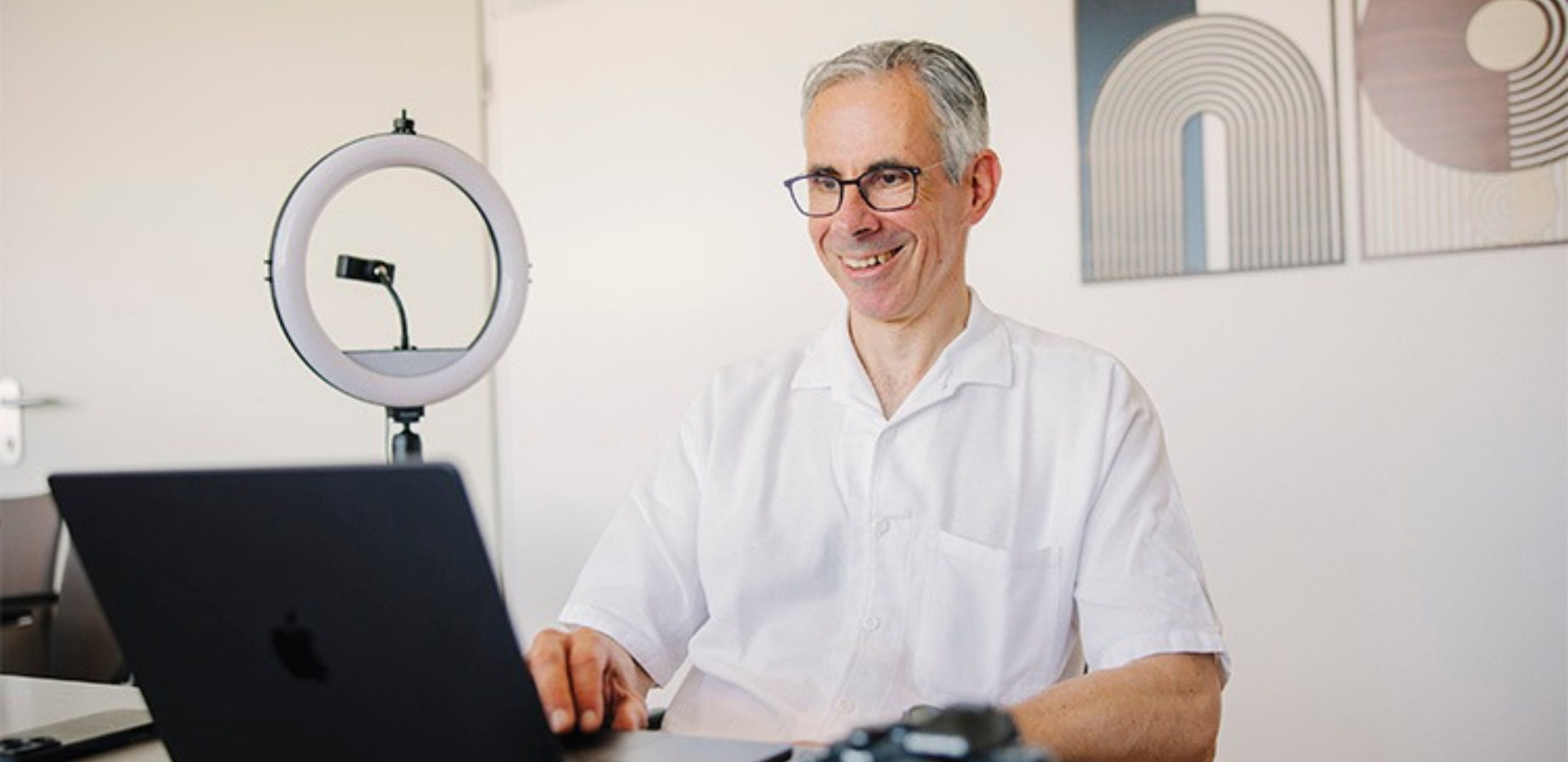 Internist Robert Königsberger schaut lächelnd auf Laptop
