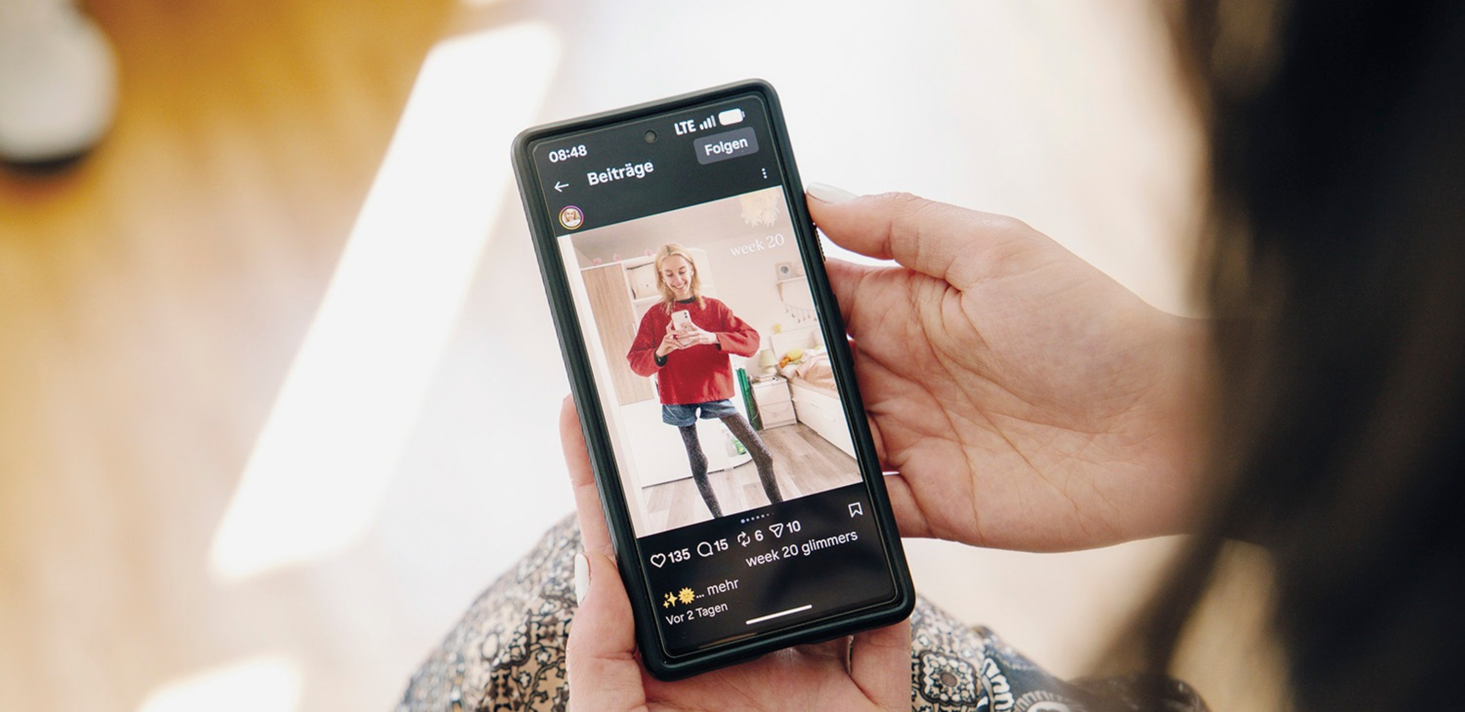 Auf Smartphone ist eine Social Media App geöffnet, Bild eines Beitrags zeigt junge Frau mit dünnen Beinen