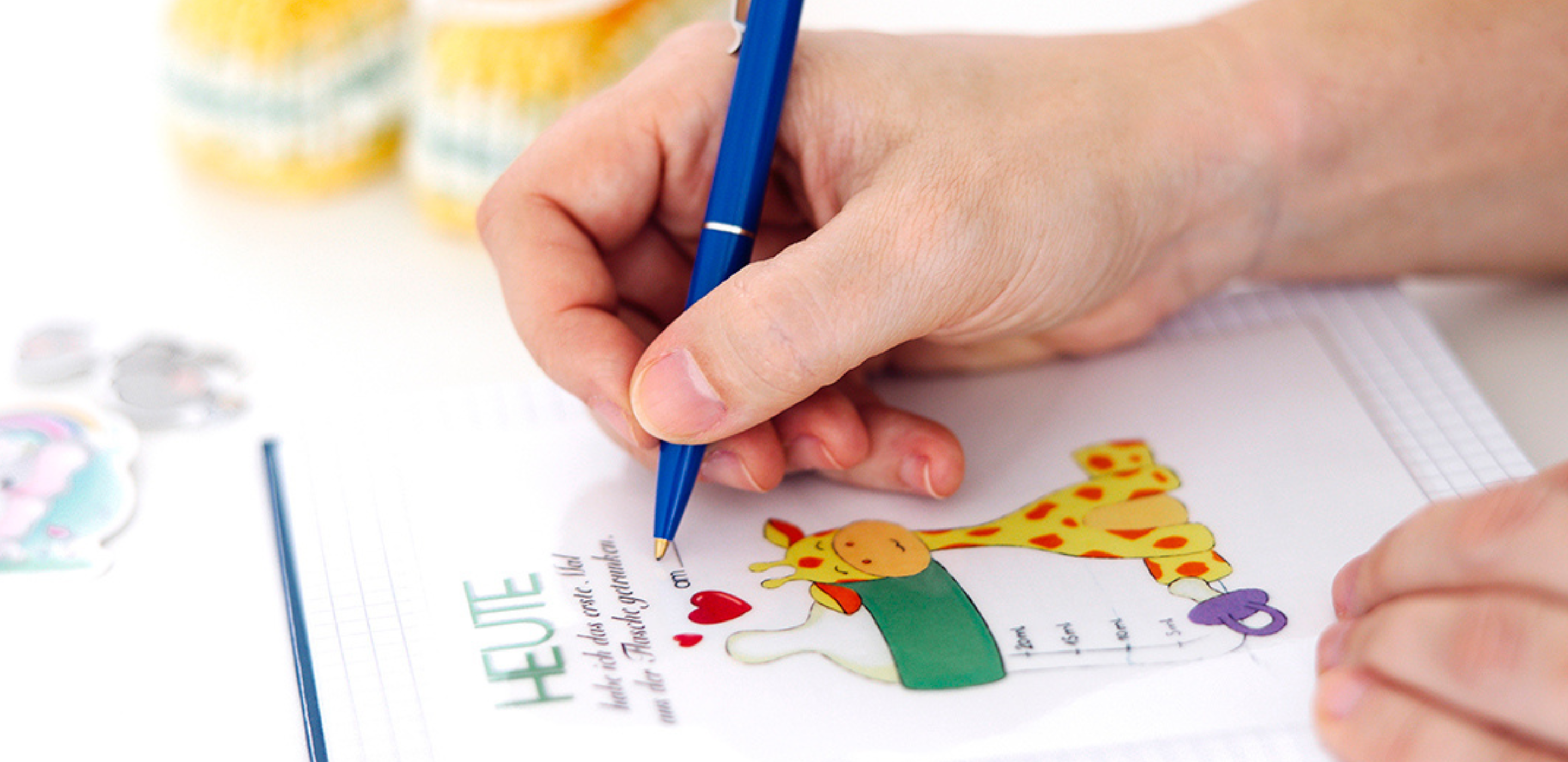 Hand schreibt mit Stift in ein Babytagebuch