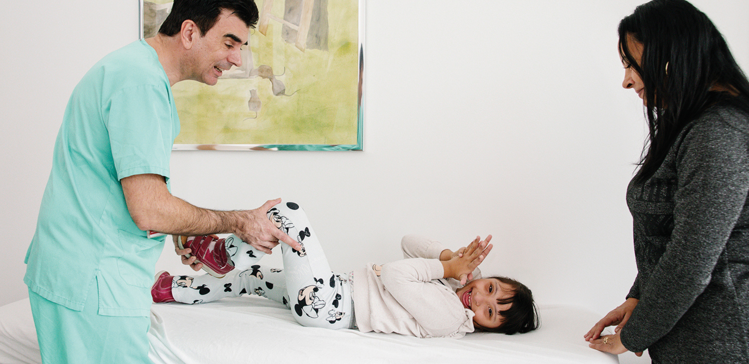 Arzt untersucht junges Mädchen, Mutter steht daneben.