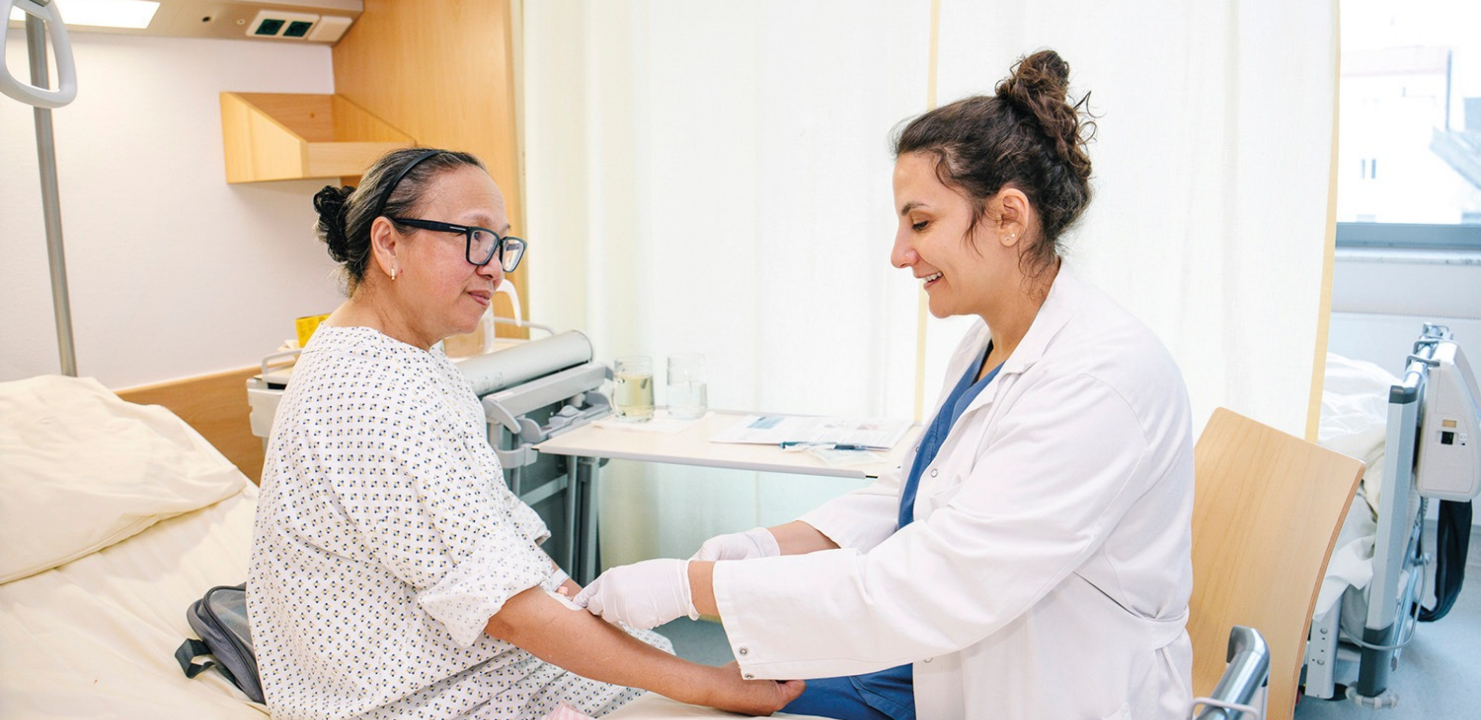 Ärztin führt Untersuchung bei Patientin in Krankenzimmer durch.