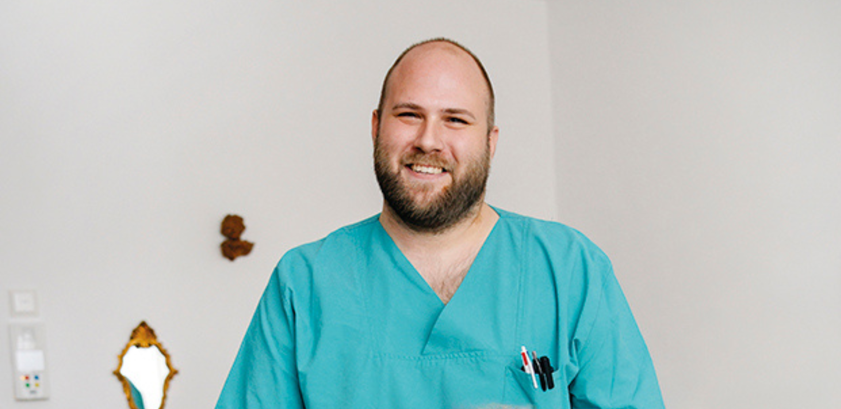 Pfleger in grüner Arbeitskleidung lächelnd